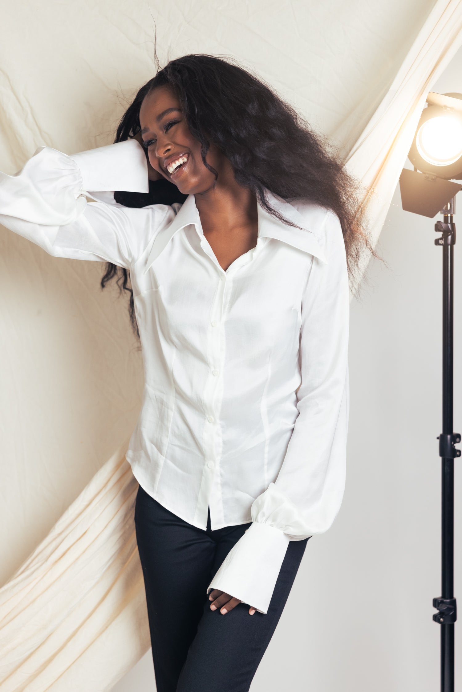 Woman wearing a white blouse and black skirt against a studio background