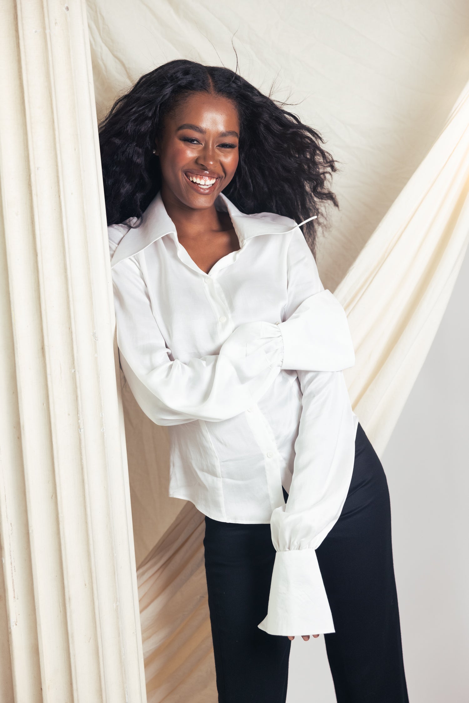 Woman wearing a white blouse and black skirt against a studio background