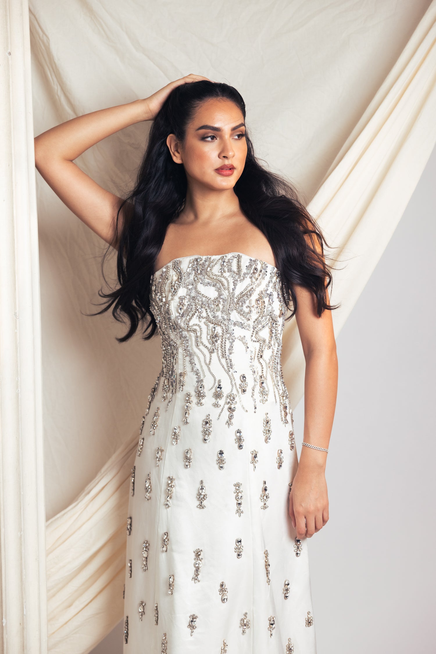 Woman wearing a strapless white dress with floral patterns on a studio background