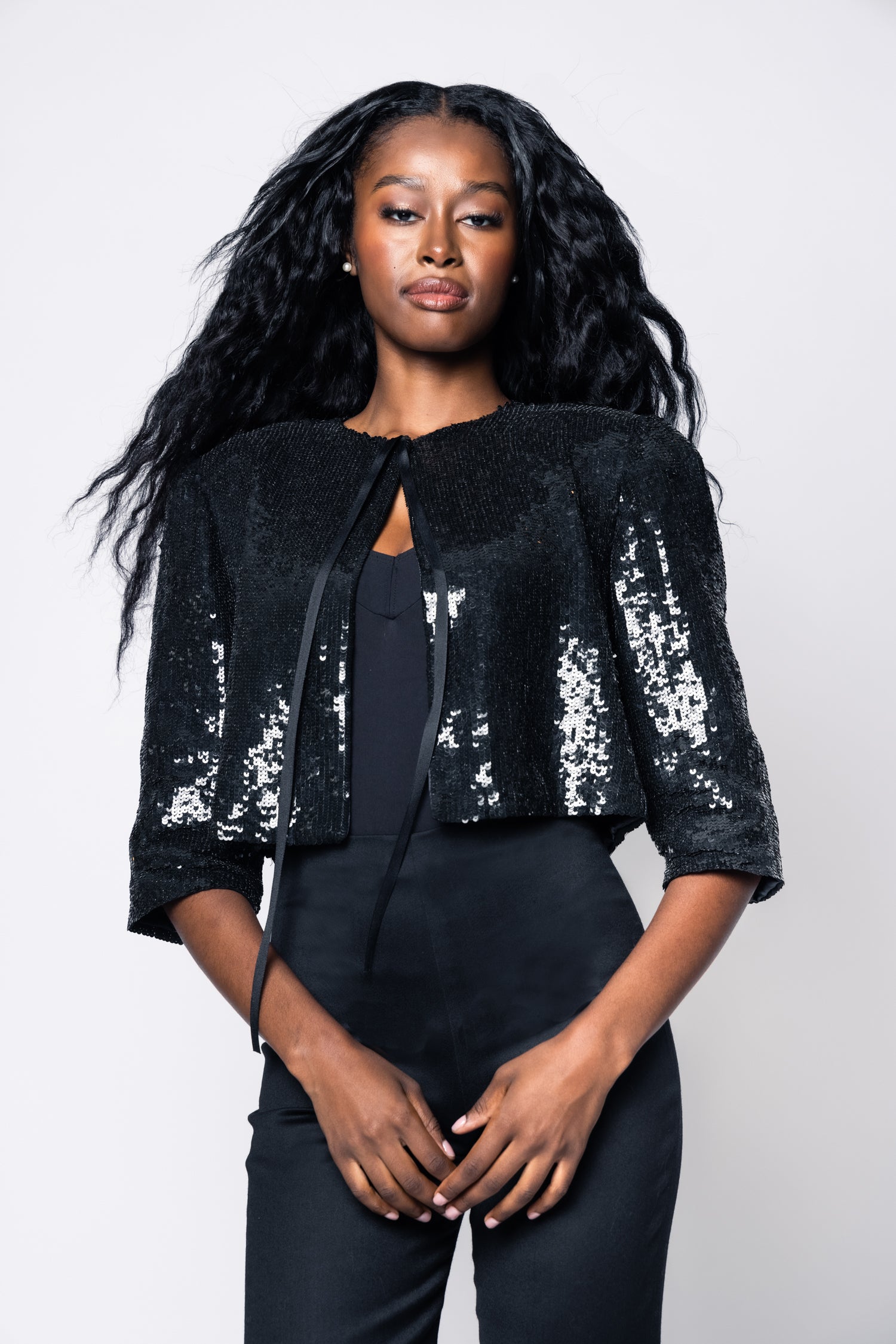 Woman wearing a black sequin jacket on a white background