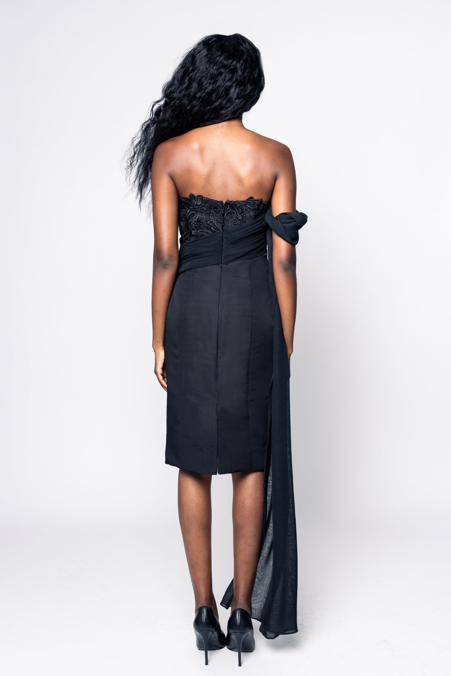 Woman wearing a black strapless dress with floral details on a white background