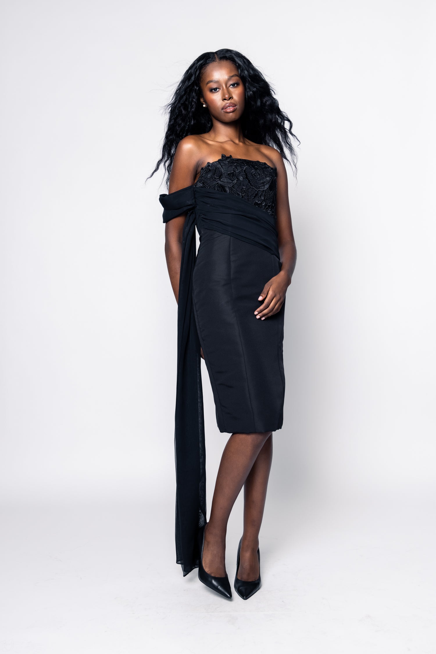 Woman wearing a black strapless dress with floral details on a white background