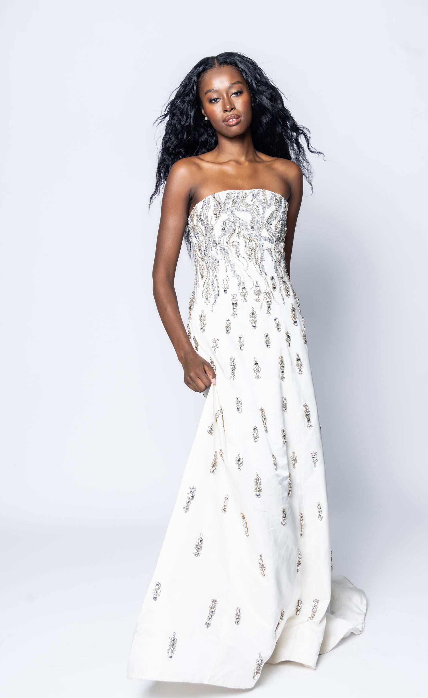 Woman wearing a strapless white dress with floral patterns on a white background