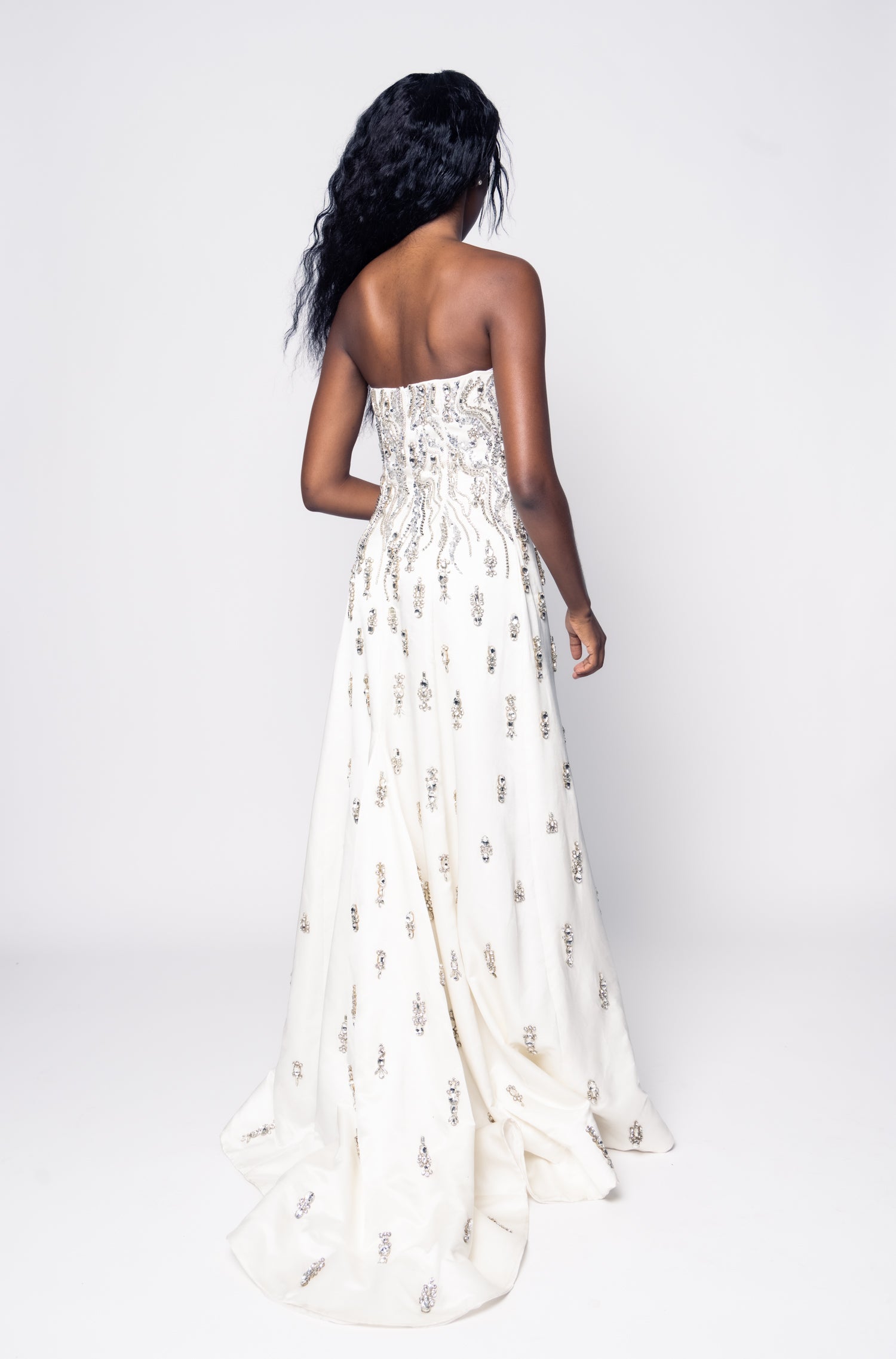 Woman wearing a strapless white dress with floral patterns on a white background