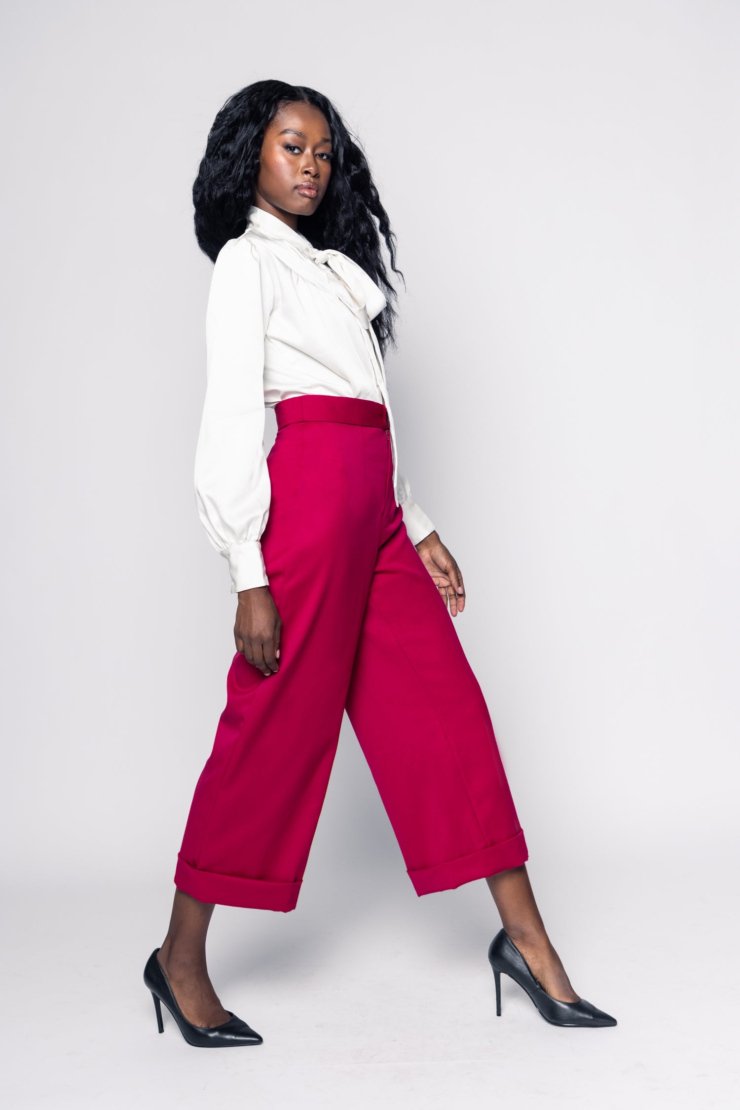 Woman wearing a white blouse and pink pants against a white background