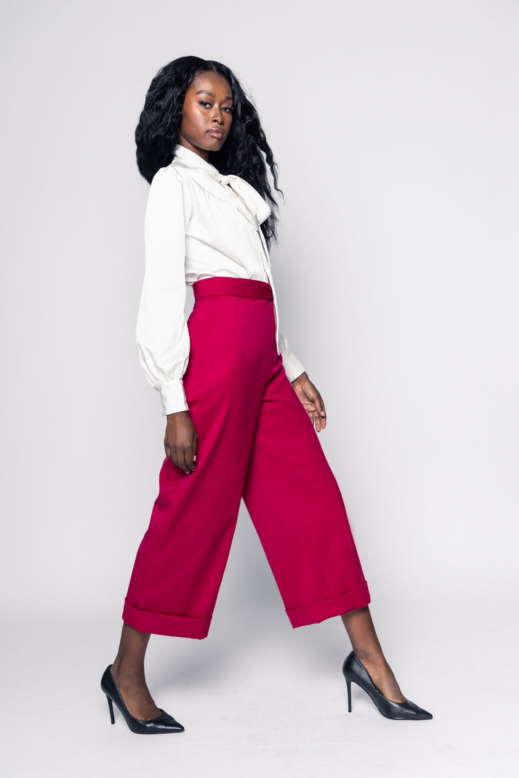 Woman wearing a white blouse and pink pants against a white background