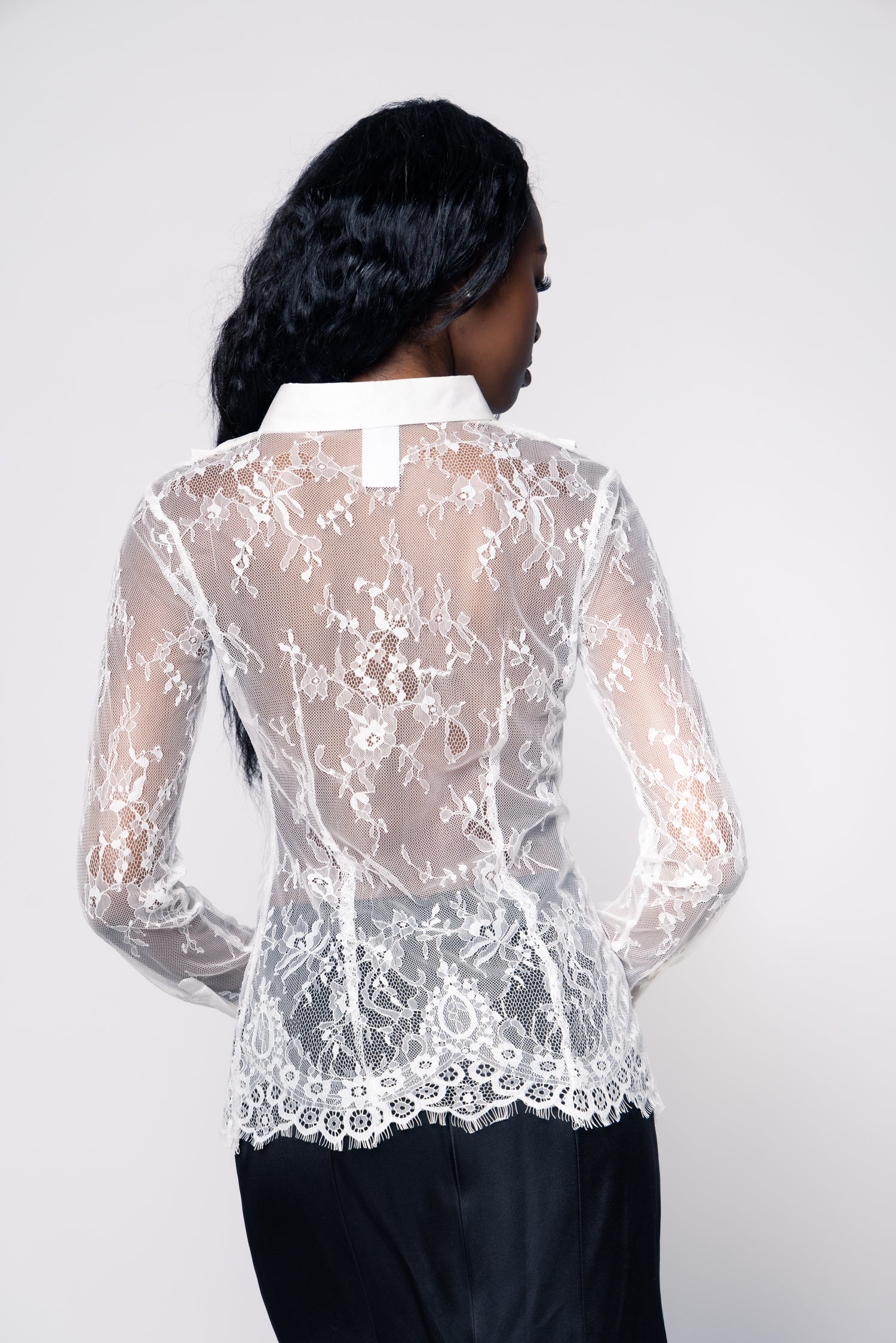 Person wearing a white lace top against a plain background