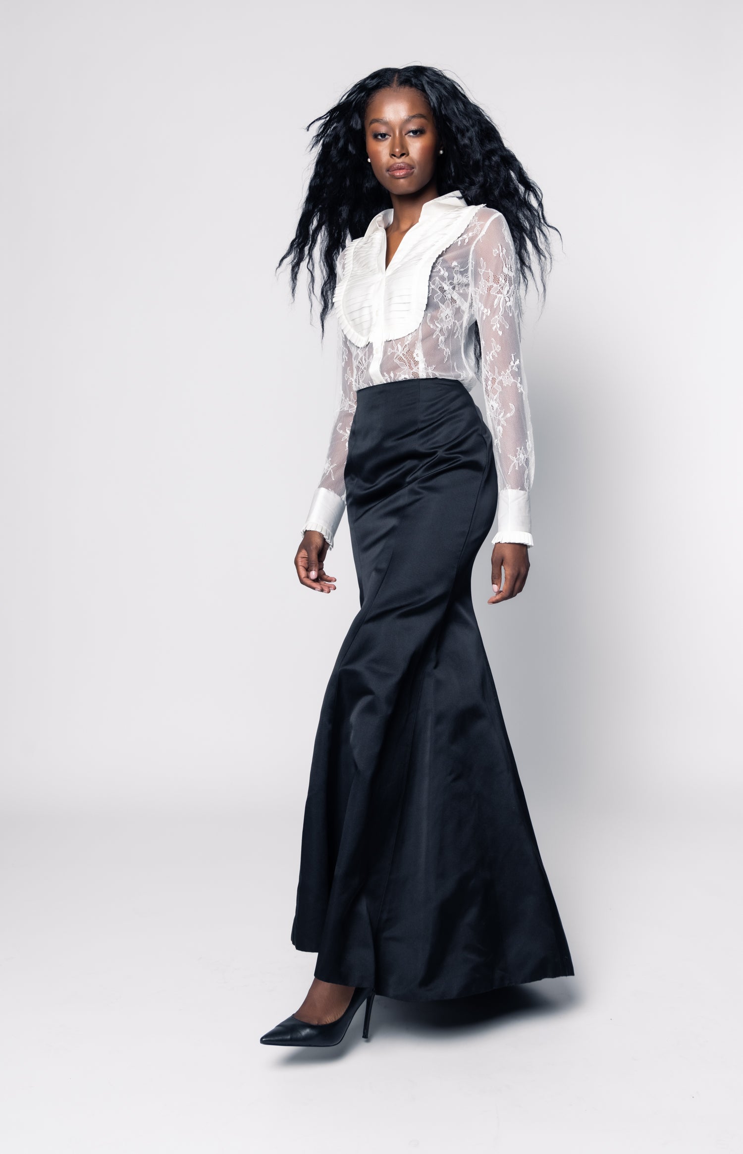 Woman wearing a black skirt and white blouse with sheer sleeves on a white background