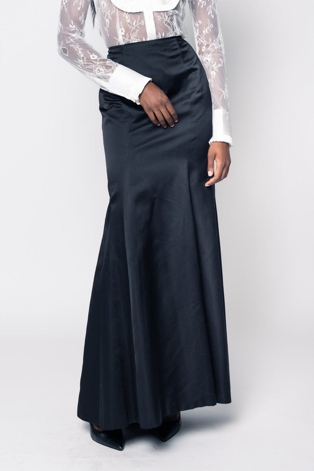 Woman wearing a white blouse with sheer sleeves and a black skirt on a white background