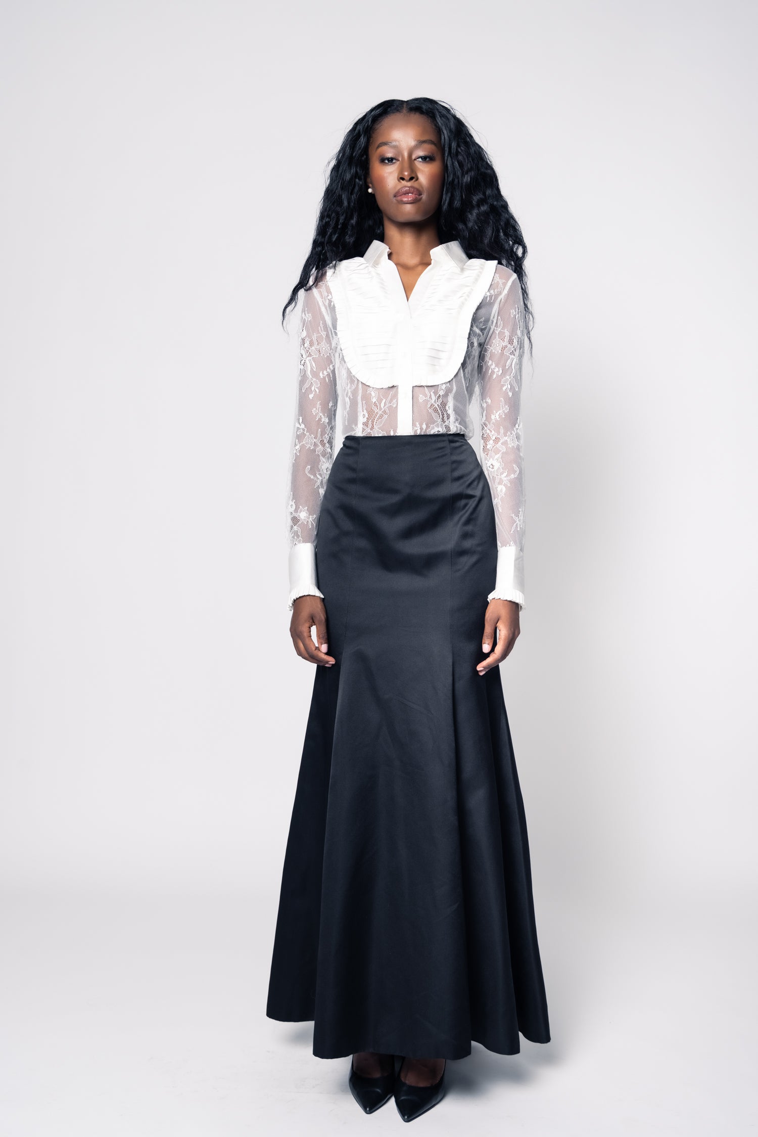 Woman wearing a white blouse with sheer sleeves and a black skirt on a white background
