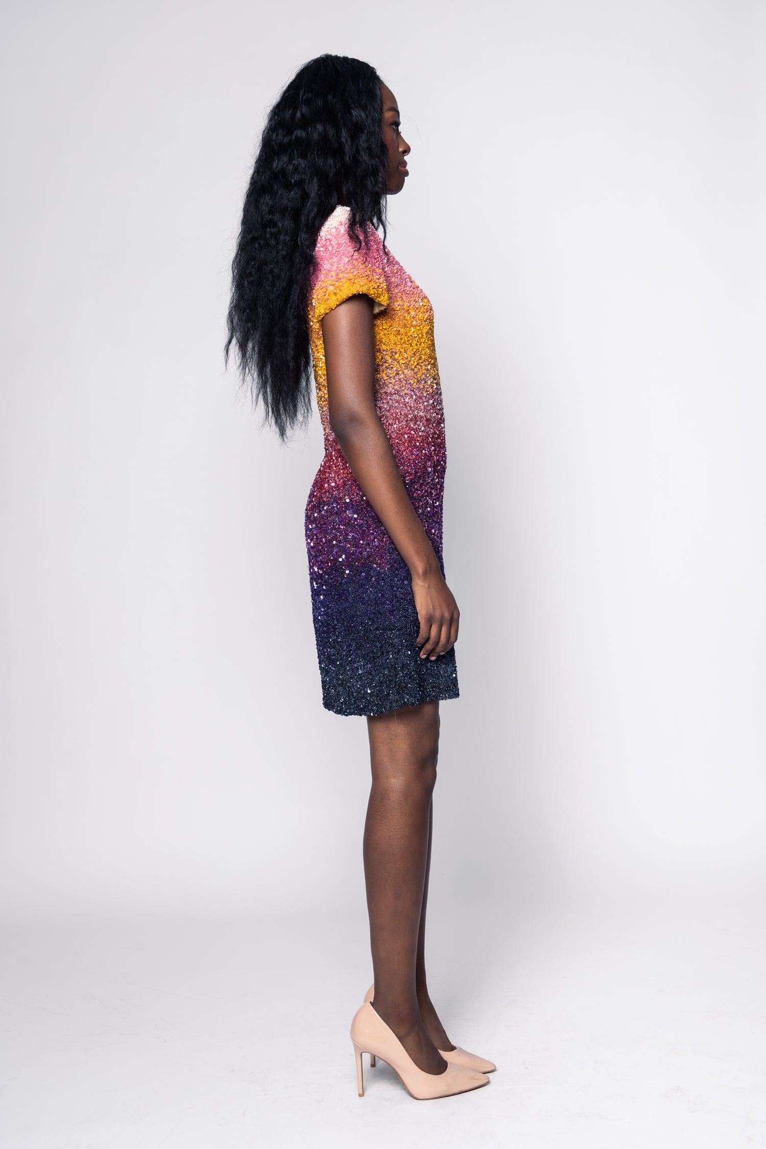 Woman wearing a colorful dress with a gradient from pink to purple on a white background