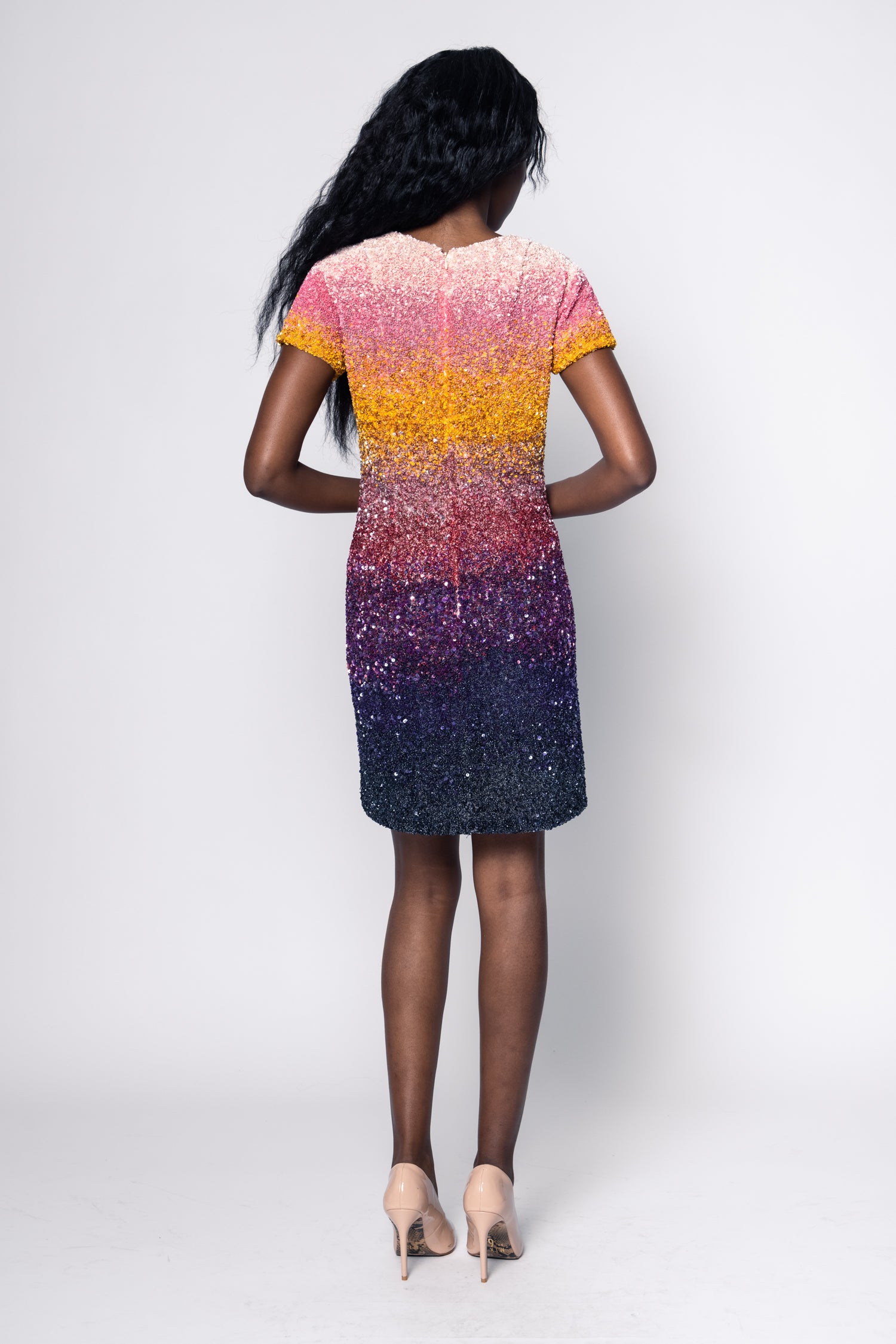 Woman wearing a colorful dress with a gradient pattern on a white background