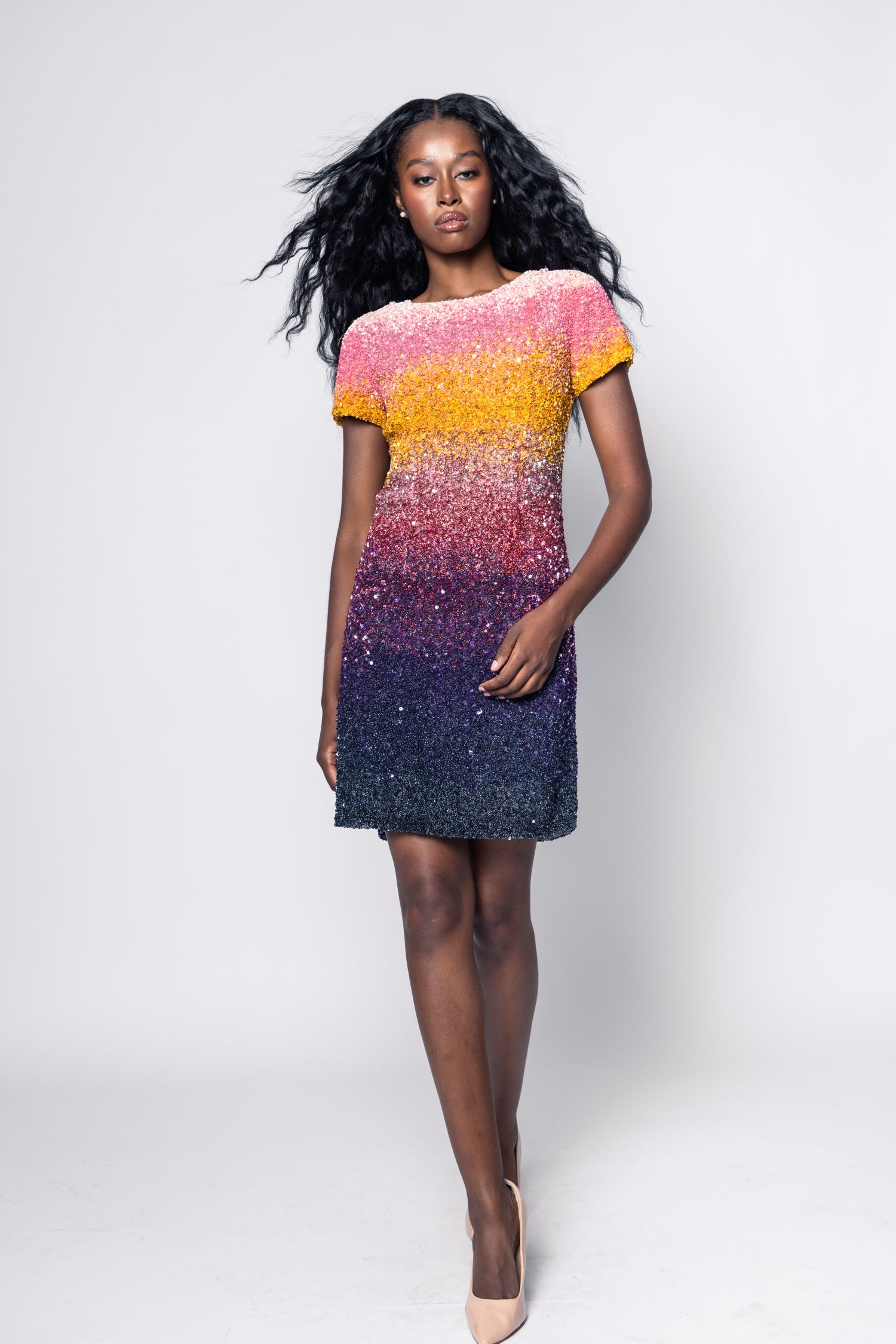 Woman wearing a colorful dress with a gradient from pink to blue on a white background