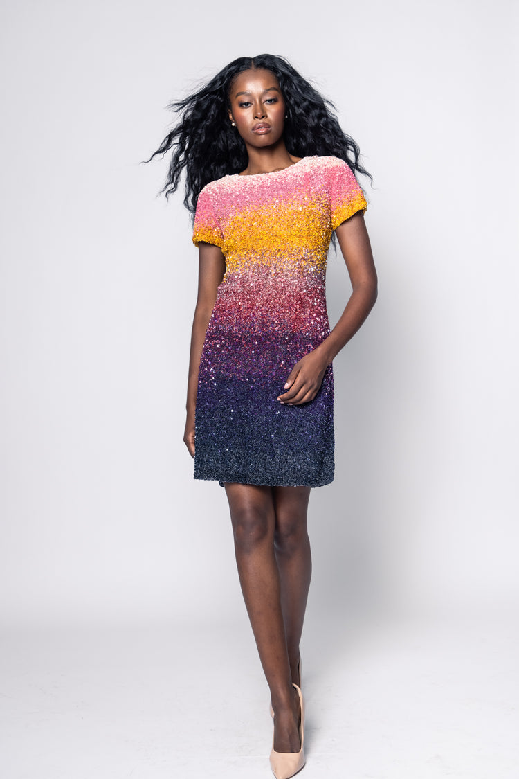 Woman wearing a colorful dress with a gradient from pink to blue on a white background