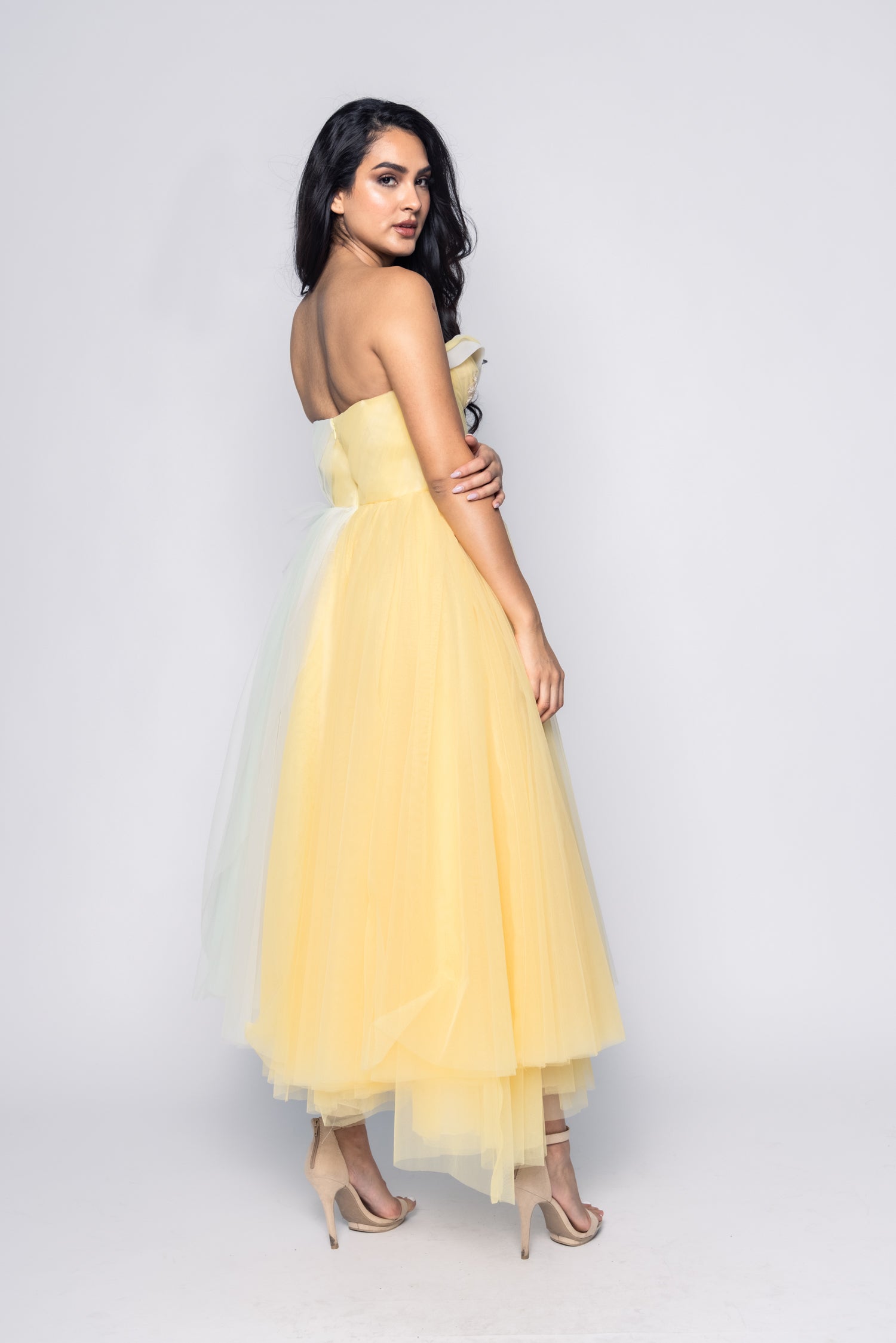 Woman wearing a yellow strapless dress on a white background