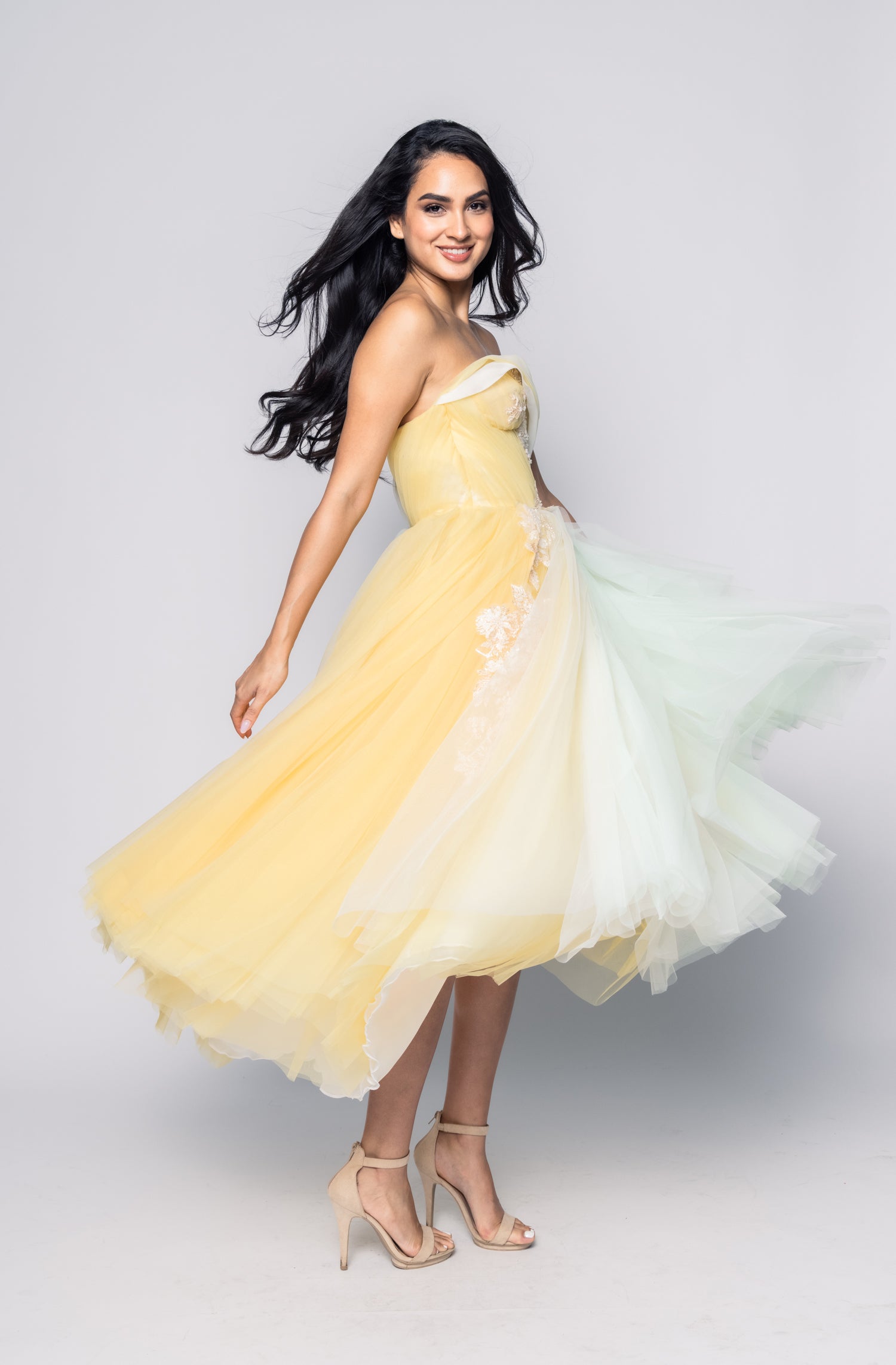 Woman wearing a yellow and white dress on a gray background