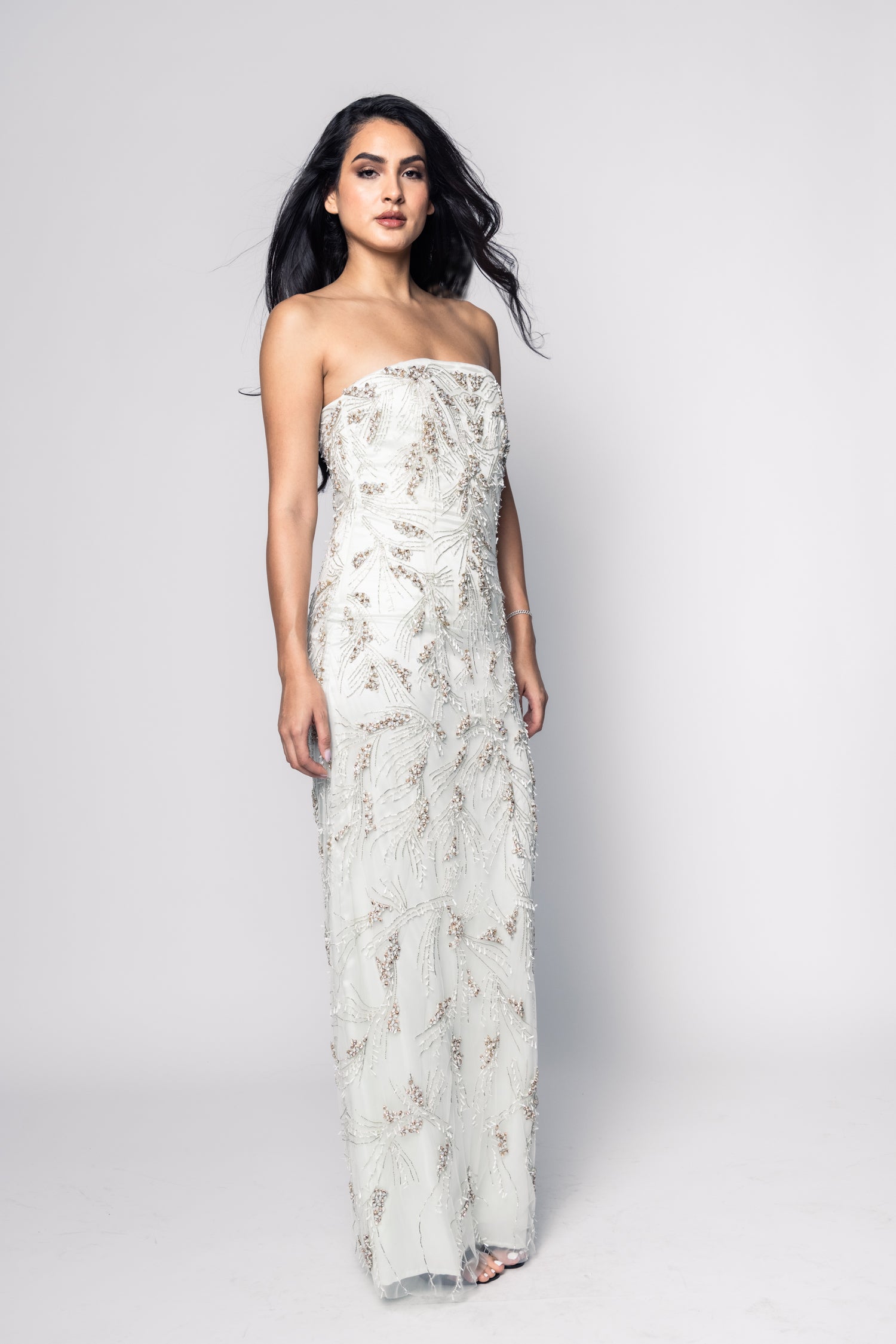 Woman wearing a strapless floral gown on a white background