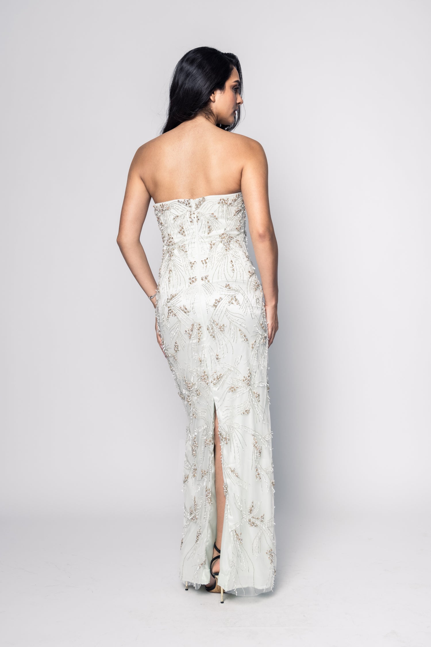 Woman wearing a strapless floral gown with a slit on a white background