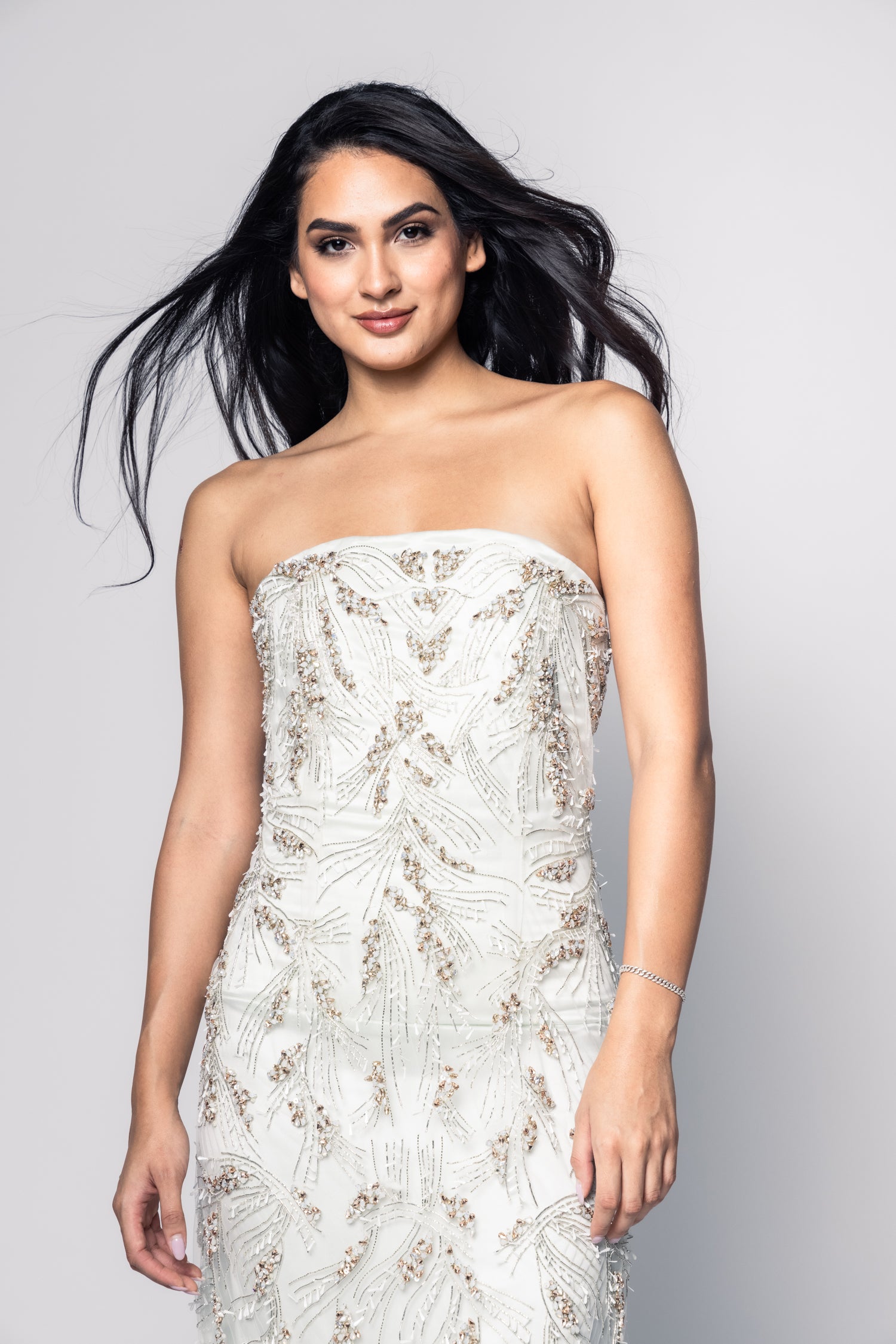 Woman wearing a strapless embroidered dress against a gray background