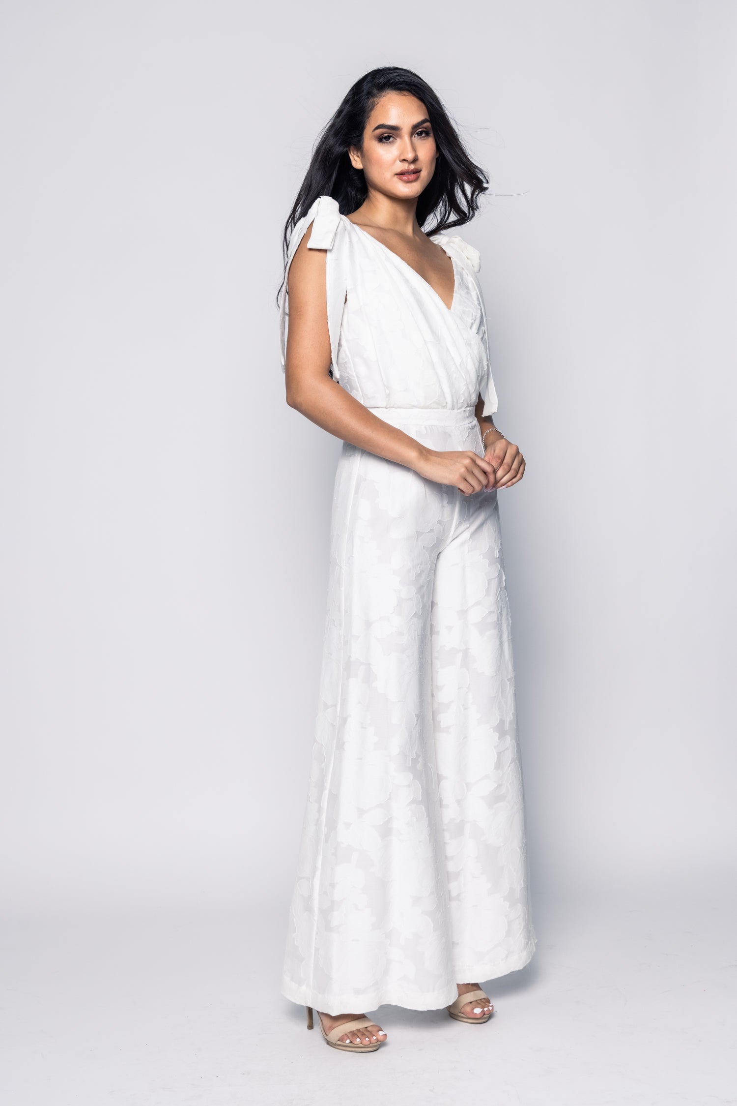 Woman wearing a white jumpsuit on a plain background