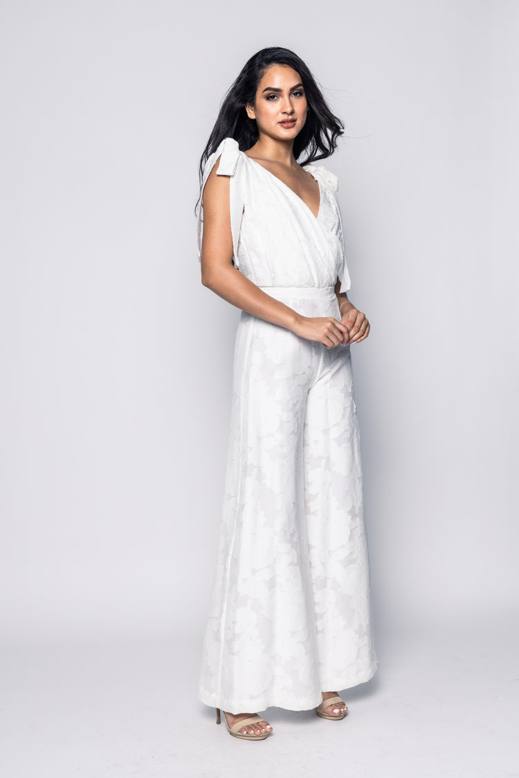 Woman wearing a white jumpsuit on a plain background