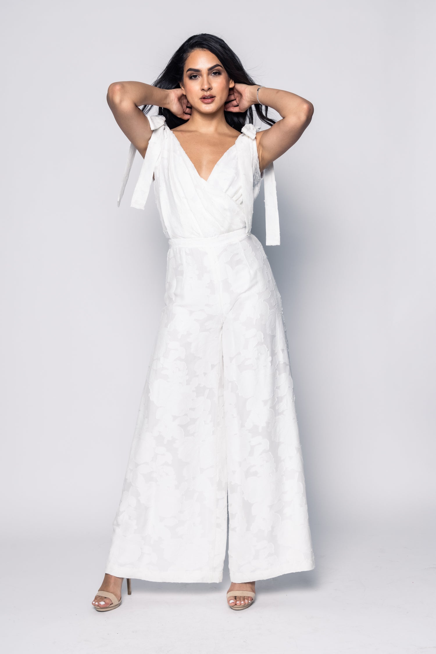 Woman wearing a white jumpsuit with a plain background
