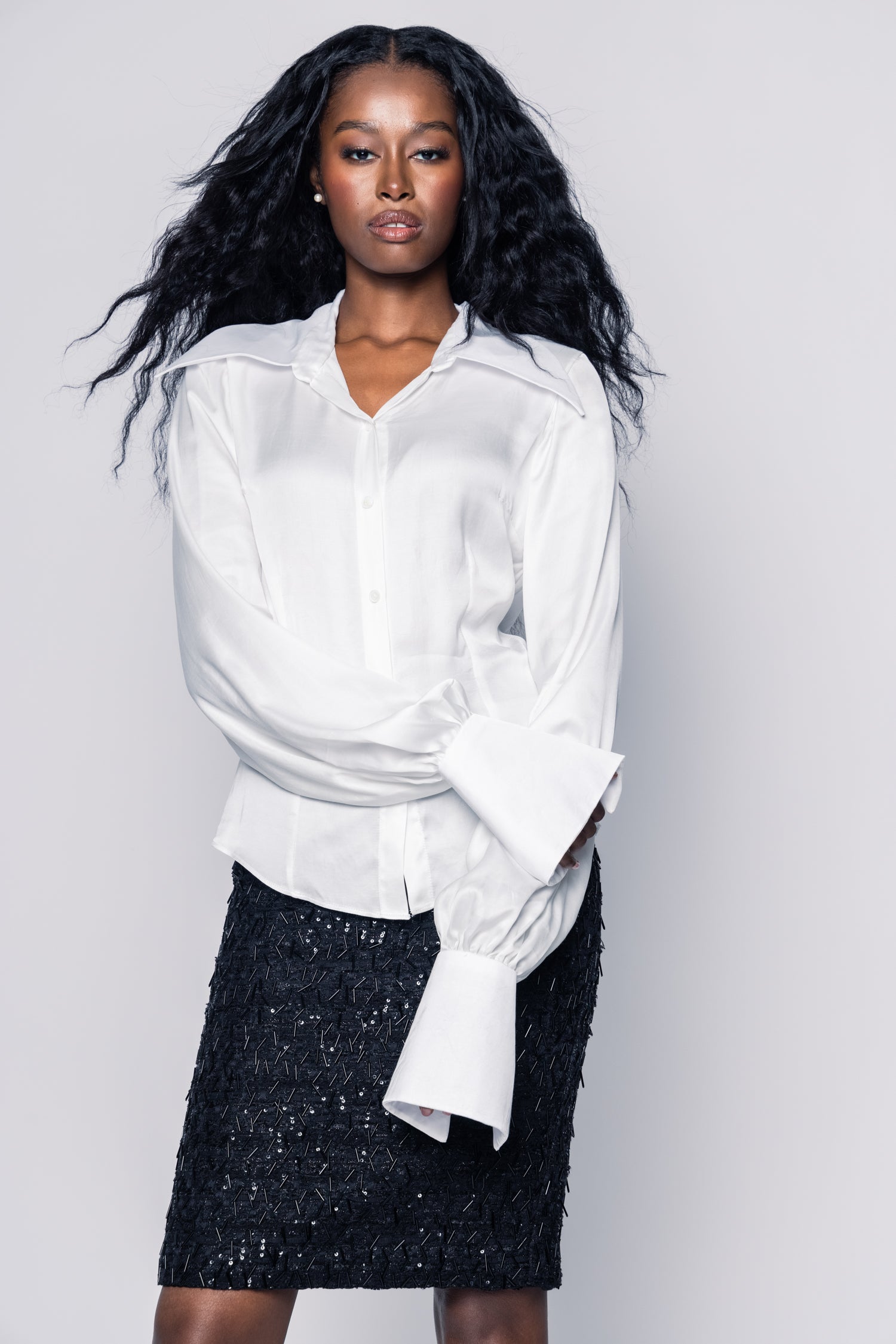 Woman wearing a white blouse and black skirt against a plain background