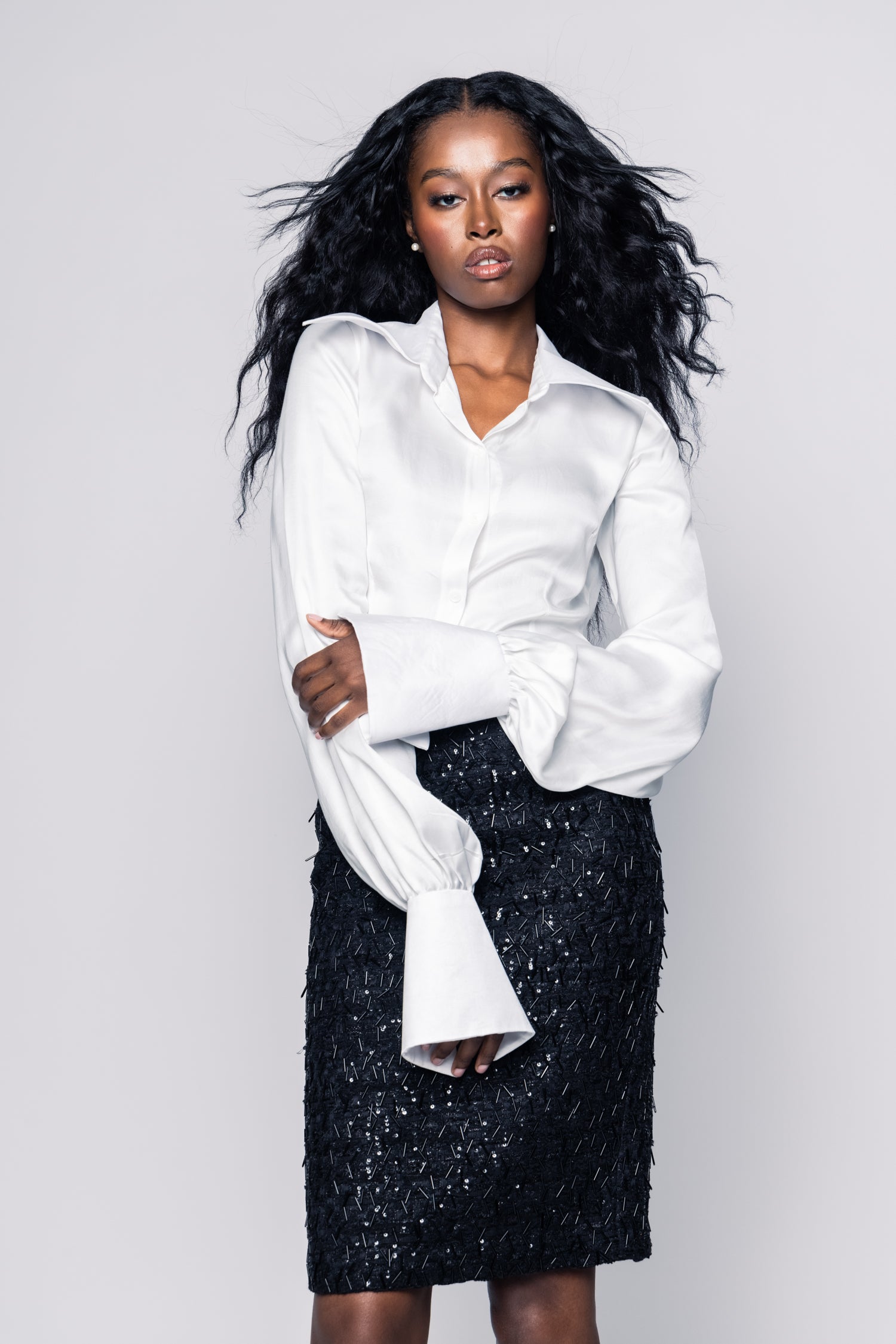 Woman wearing a white shirt and black skirt against a plain background