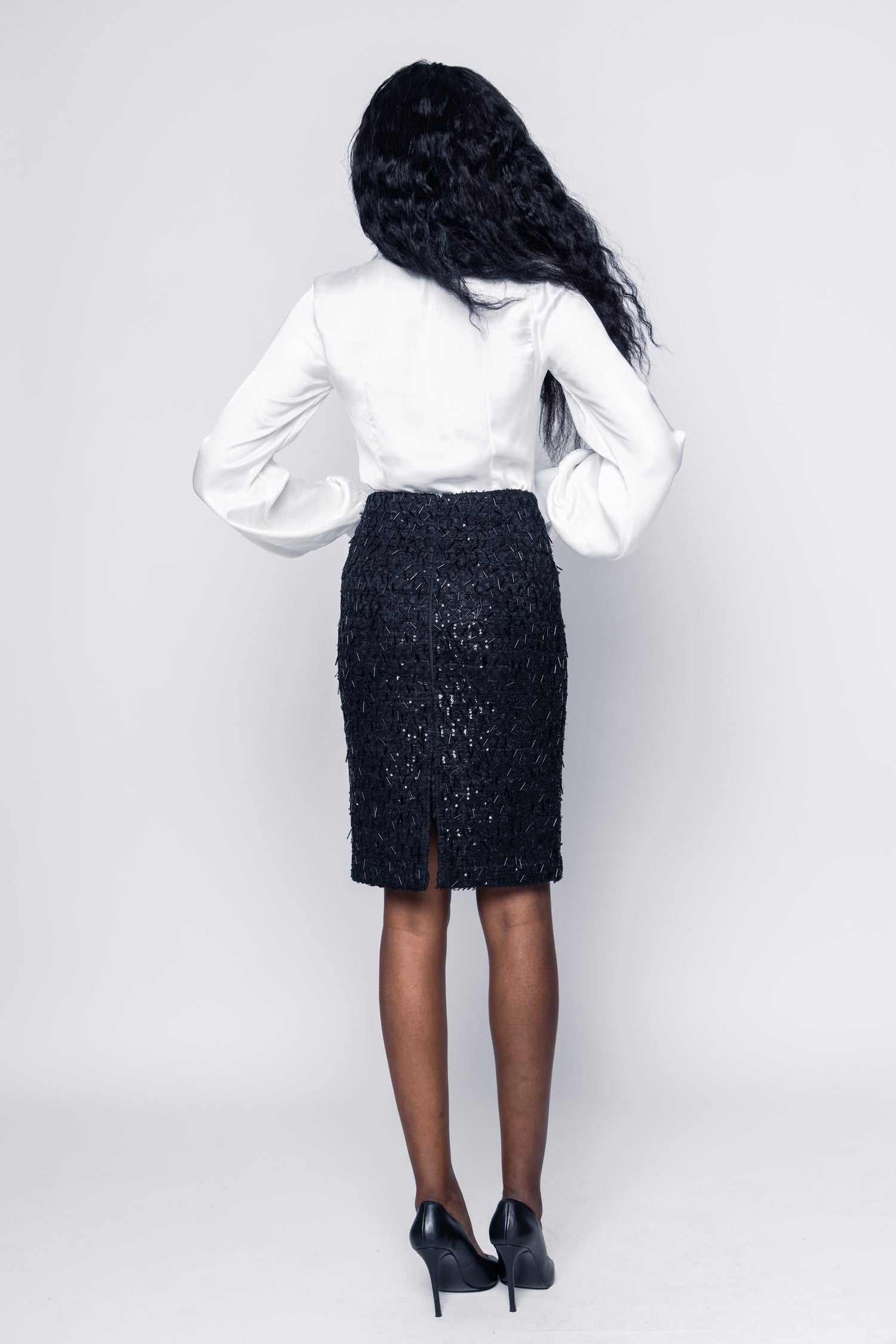 Person wearing a white blouse and black skirt on a plain background