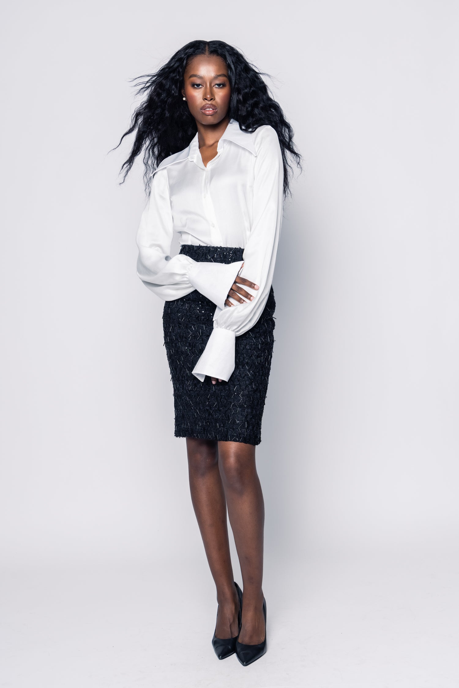 Woman wearing a white blouse and black patterned skirt on a white background