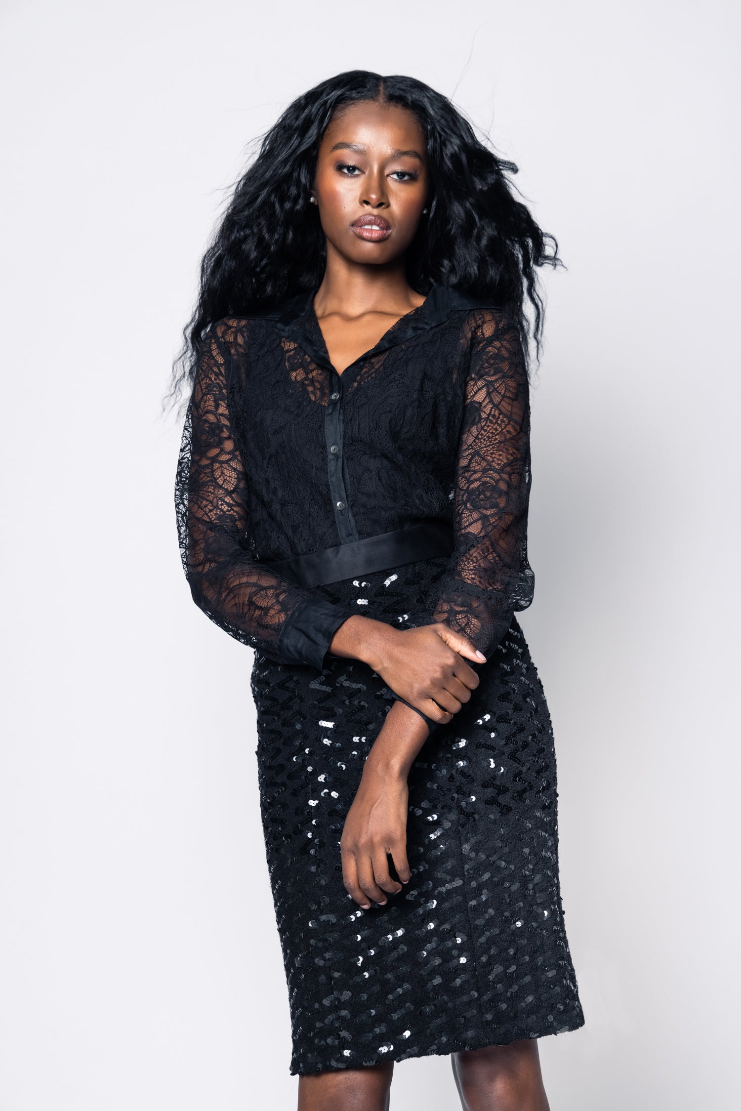 Woman wearing a black lace dress against a white background