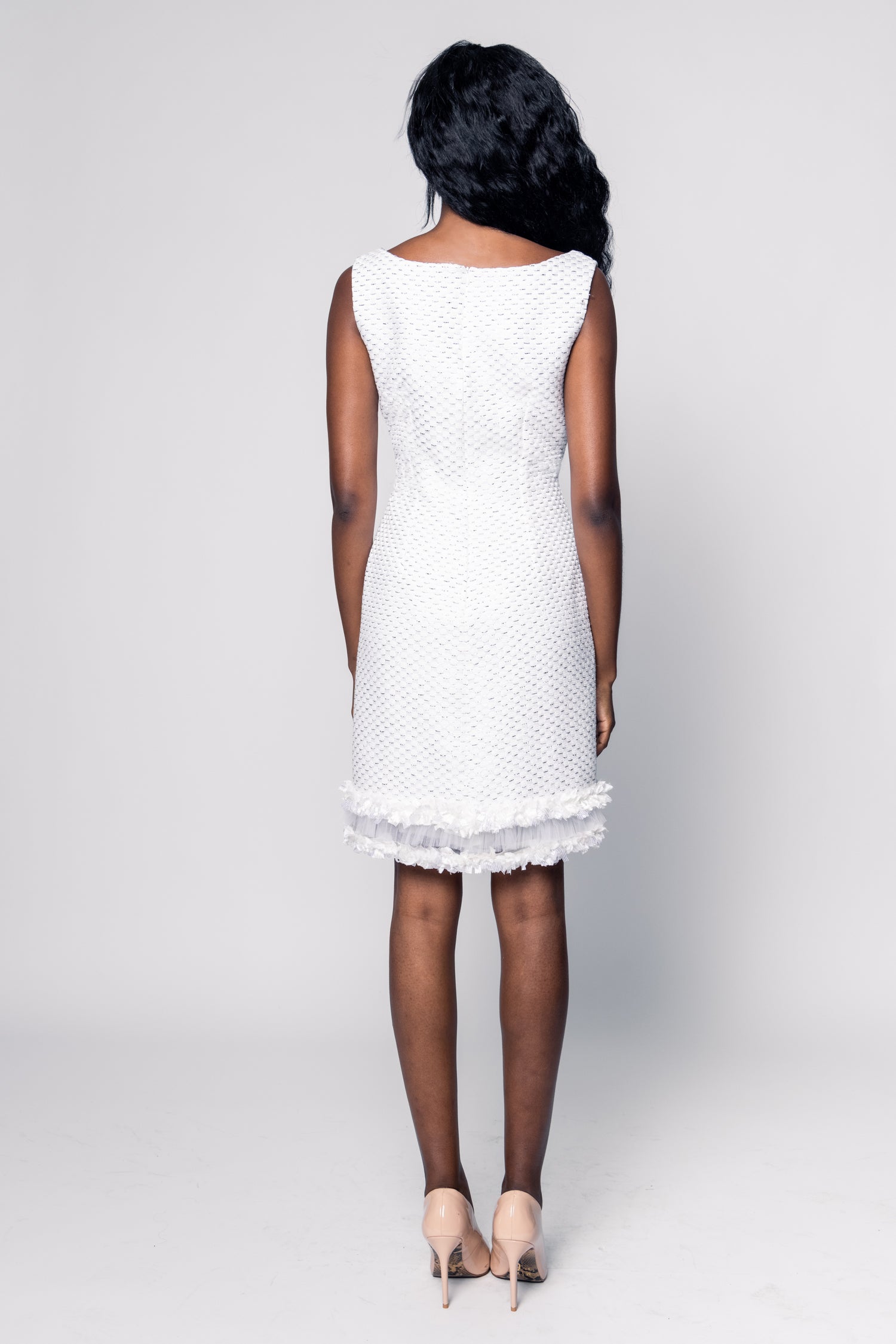 Woman wearing a white dress with lace details on a plain background
