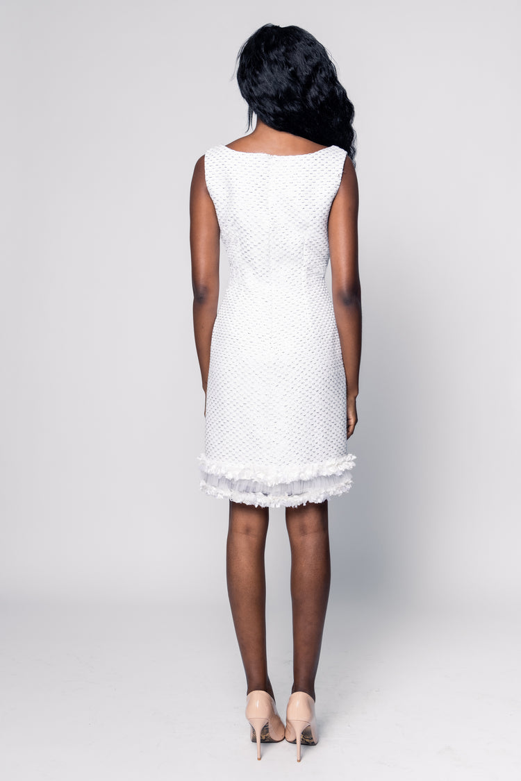 Woman wearing a white dress with lace details on a plain background