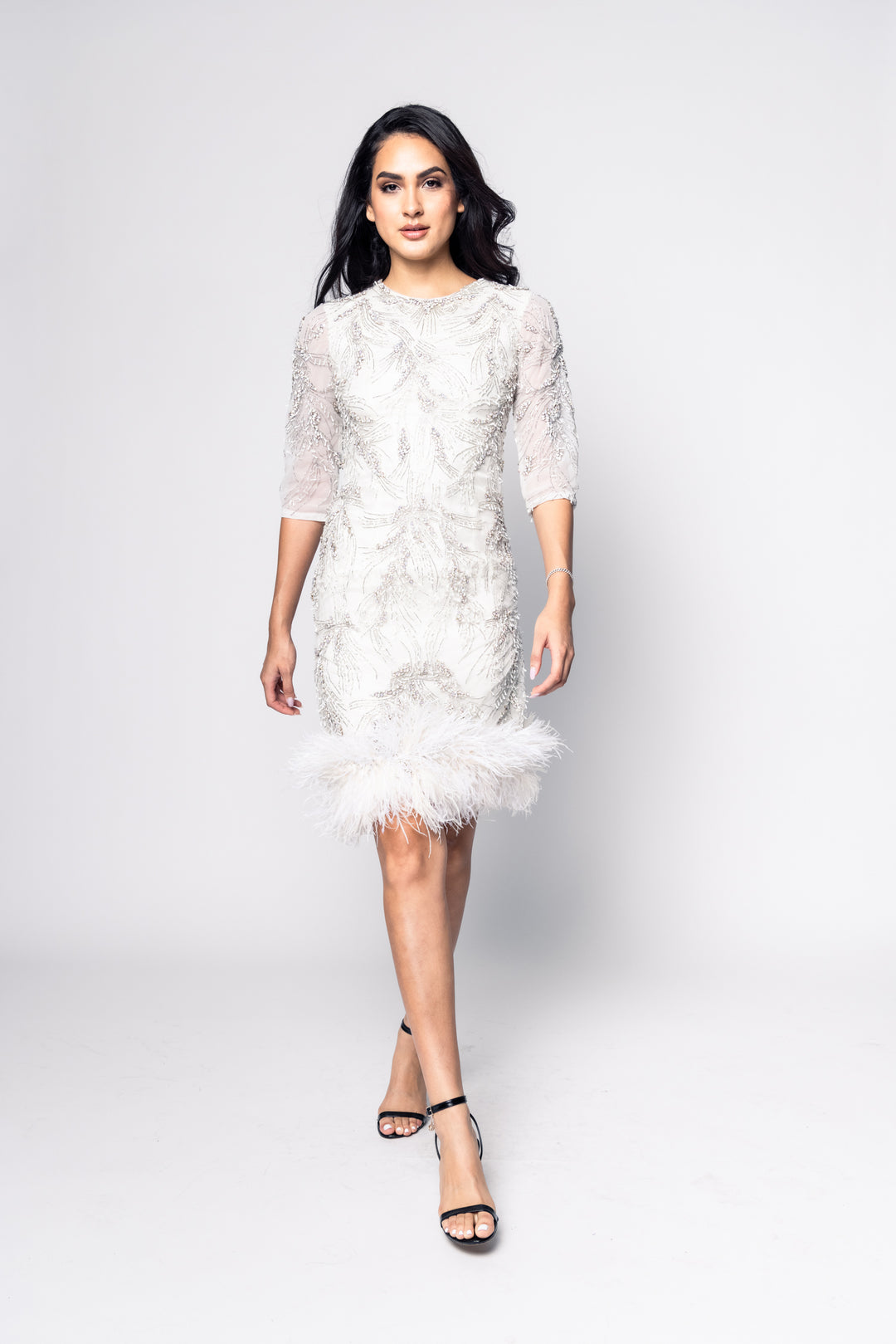 Woman wearing a white lace dress on a plain background