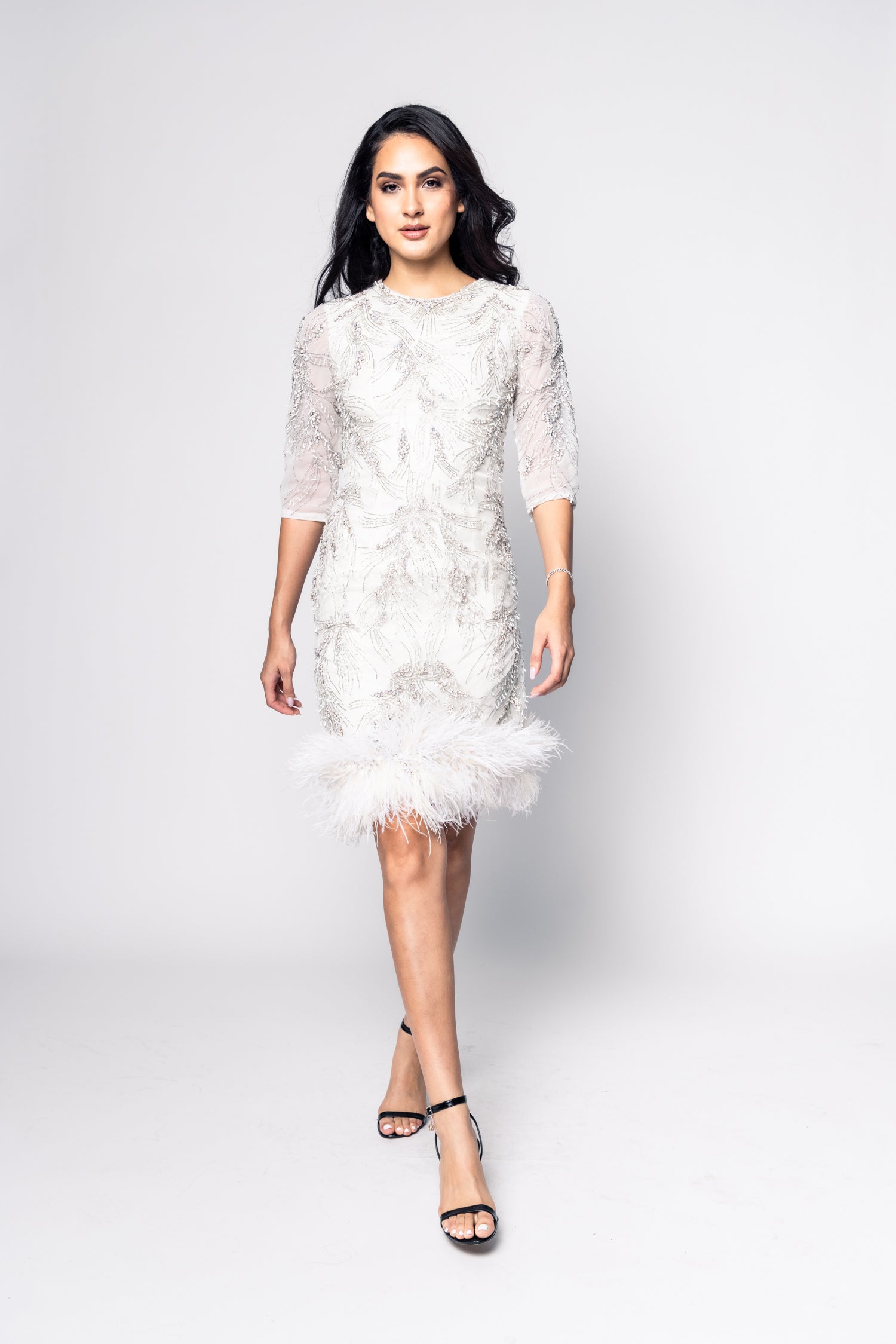 Woman wearing a white lace dress on a plain background