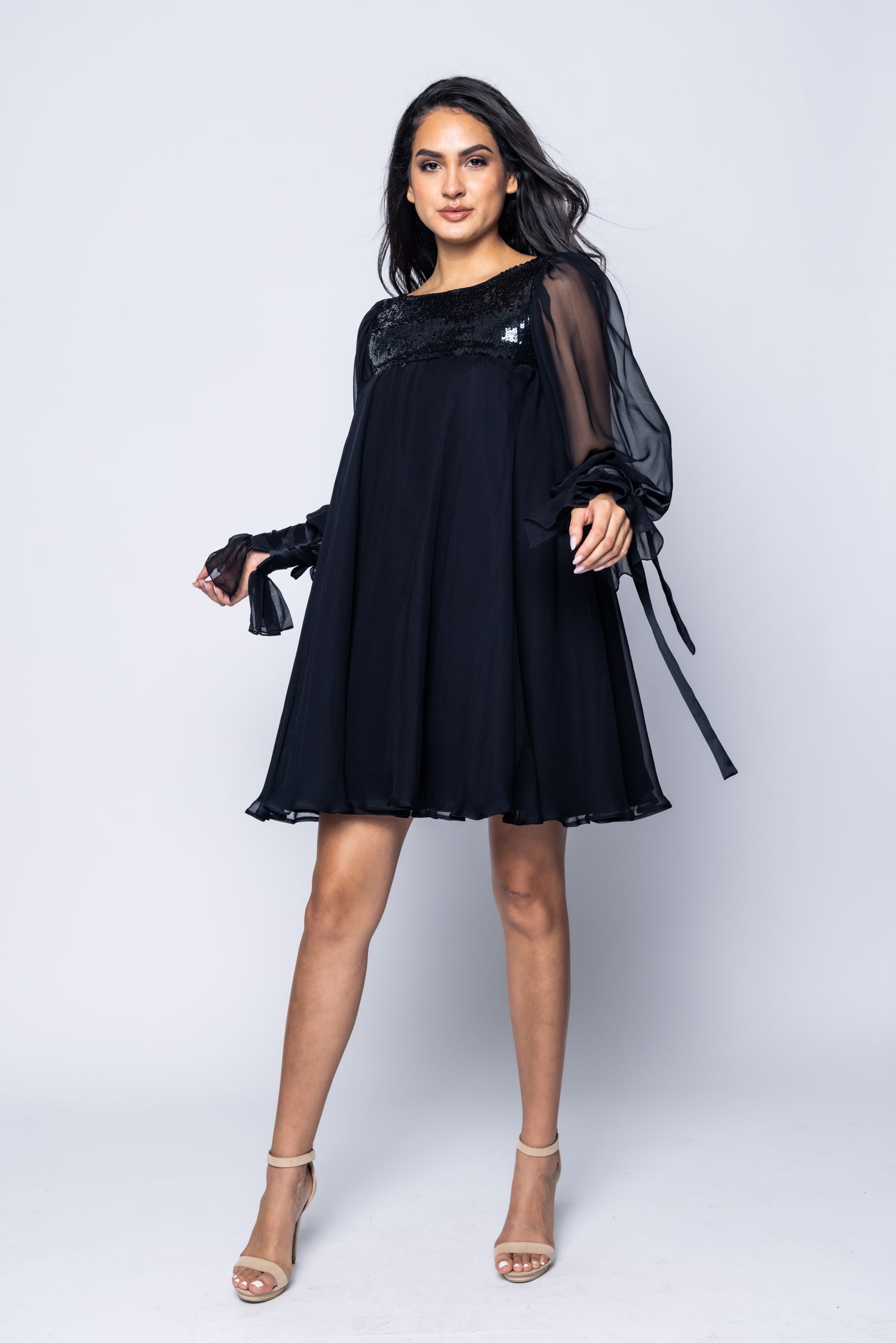 Woman wearing a black dress with sheer sleeves on a white background