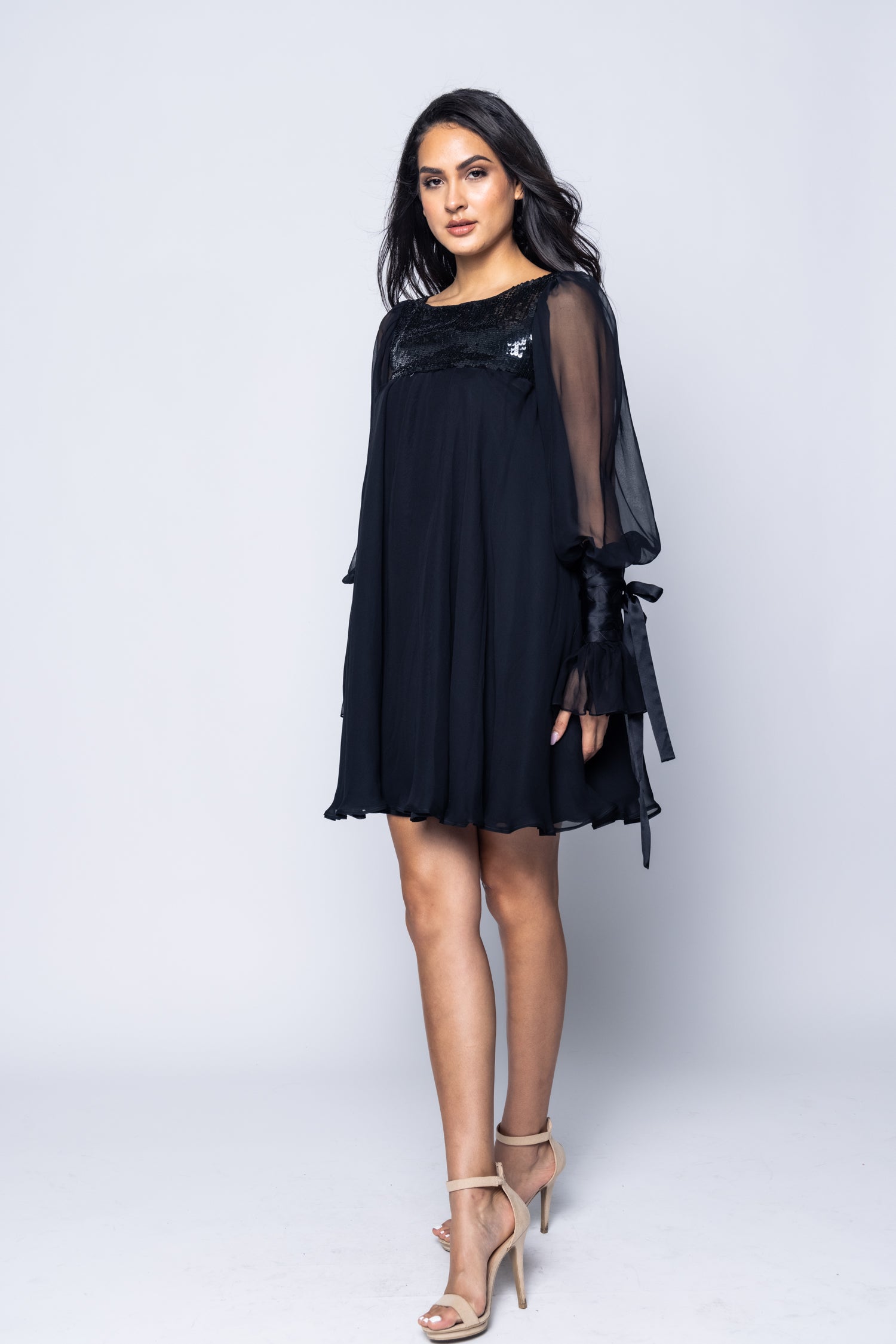 Woman wearing a black dress with sheer sleeves on a white background