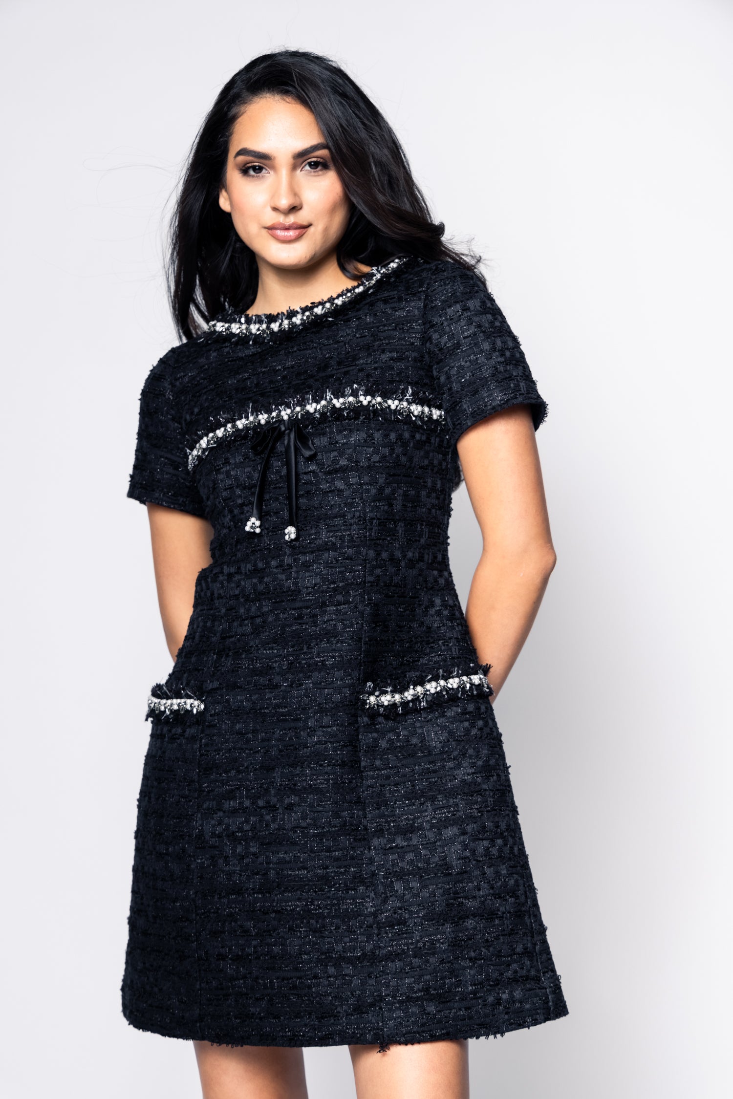 Woman wearing a black dress with silver embellishments on a white background