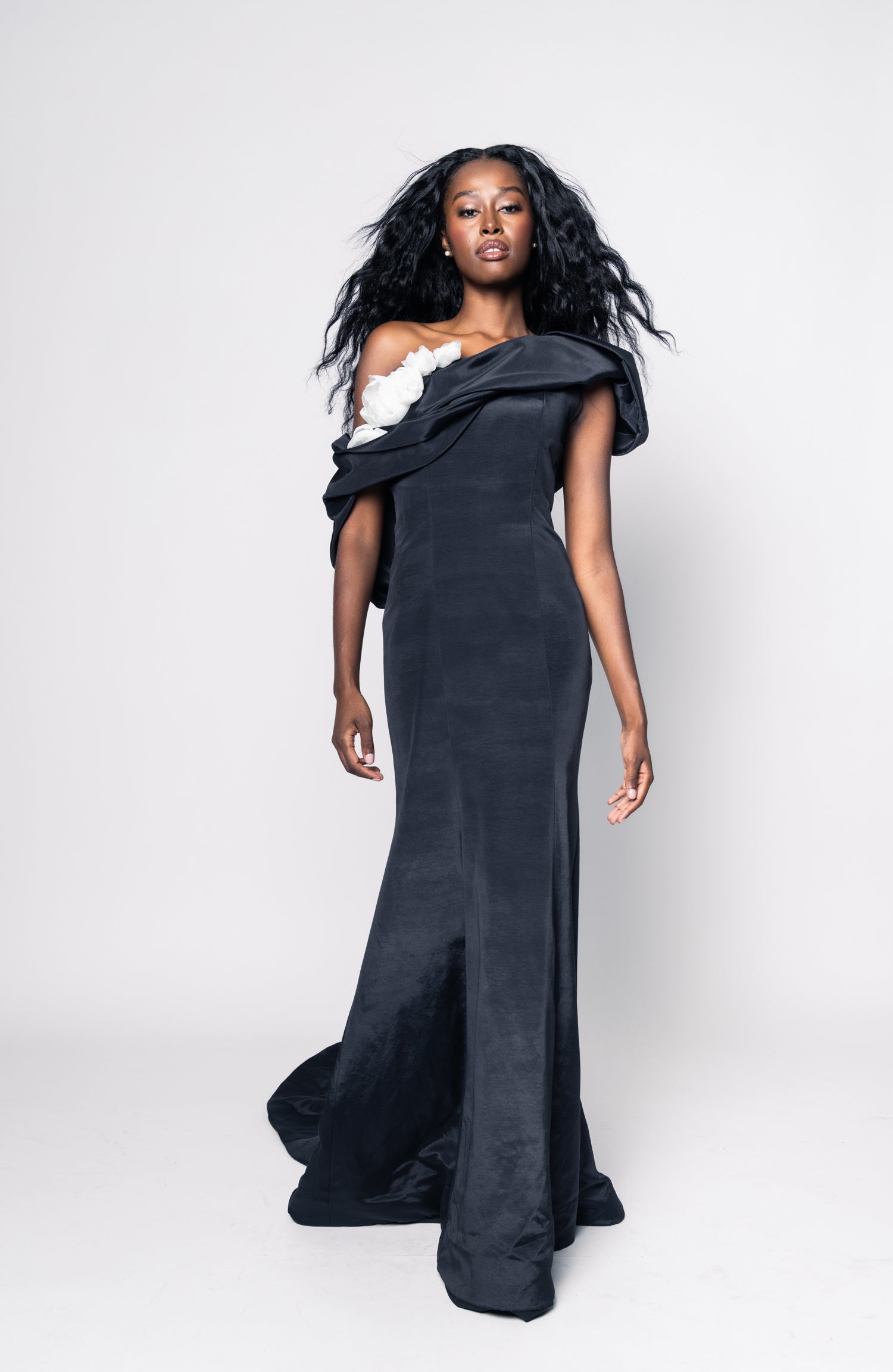 Woman wearing a black evening gown with floral details on a white background