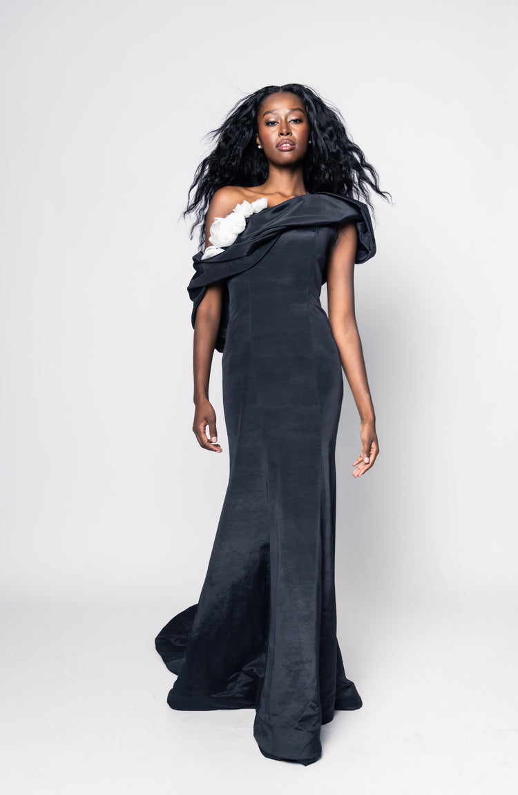 Woman wearing a black evening gown with floral details on a white background