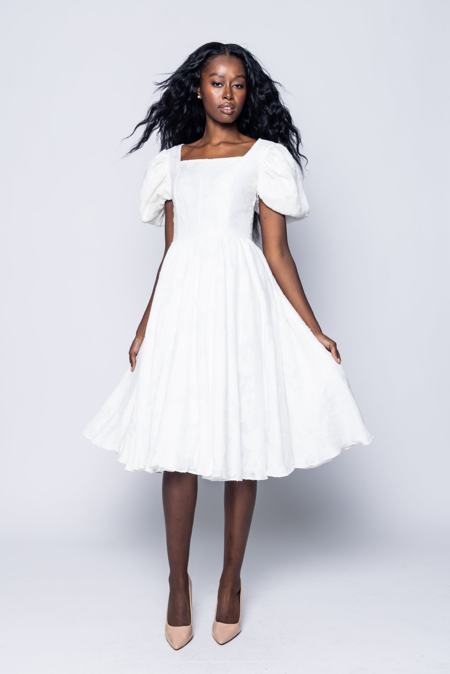 Woman wearing a white dress against a plain background