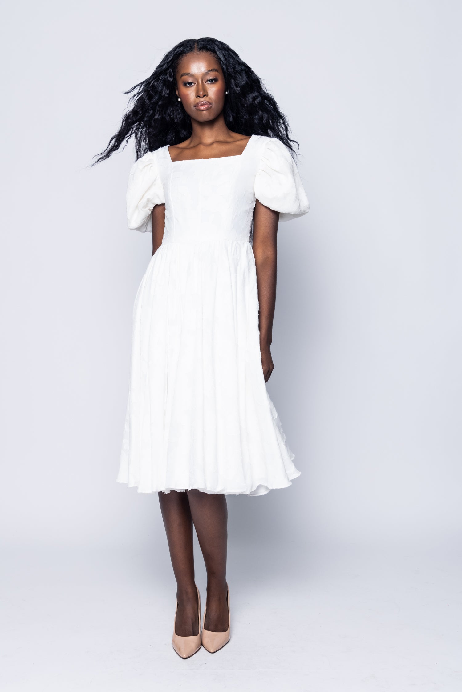 Woman wearing a white dress against a plain background