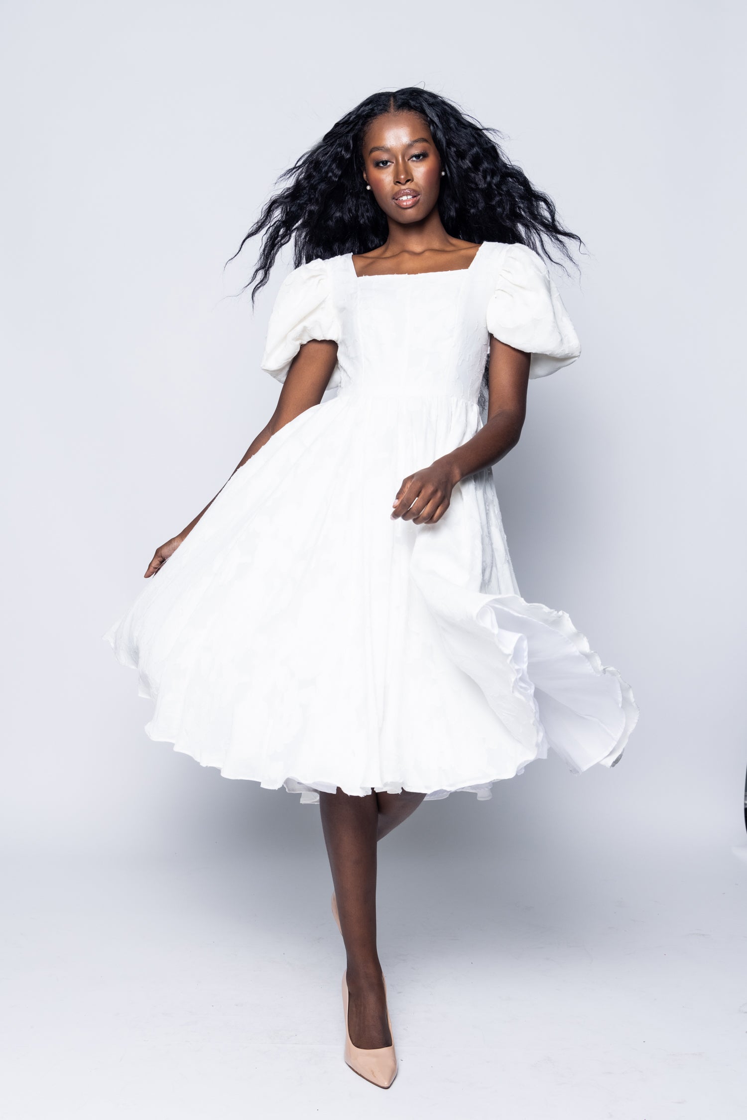Woman wearing a white dress against a plain background
