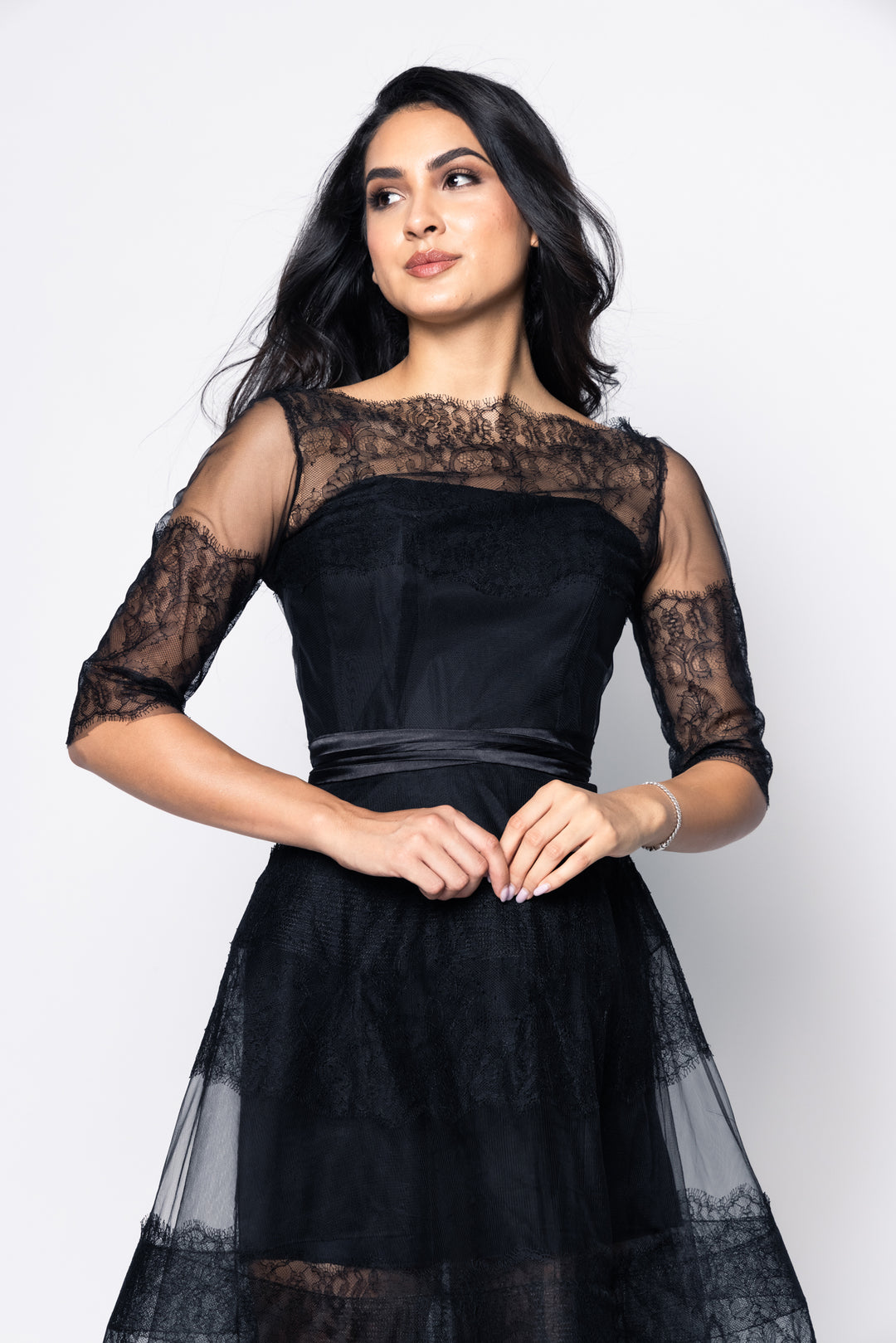 Woman wearing a black lace dress against a white background