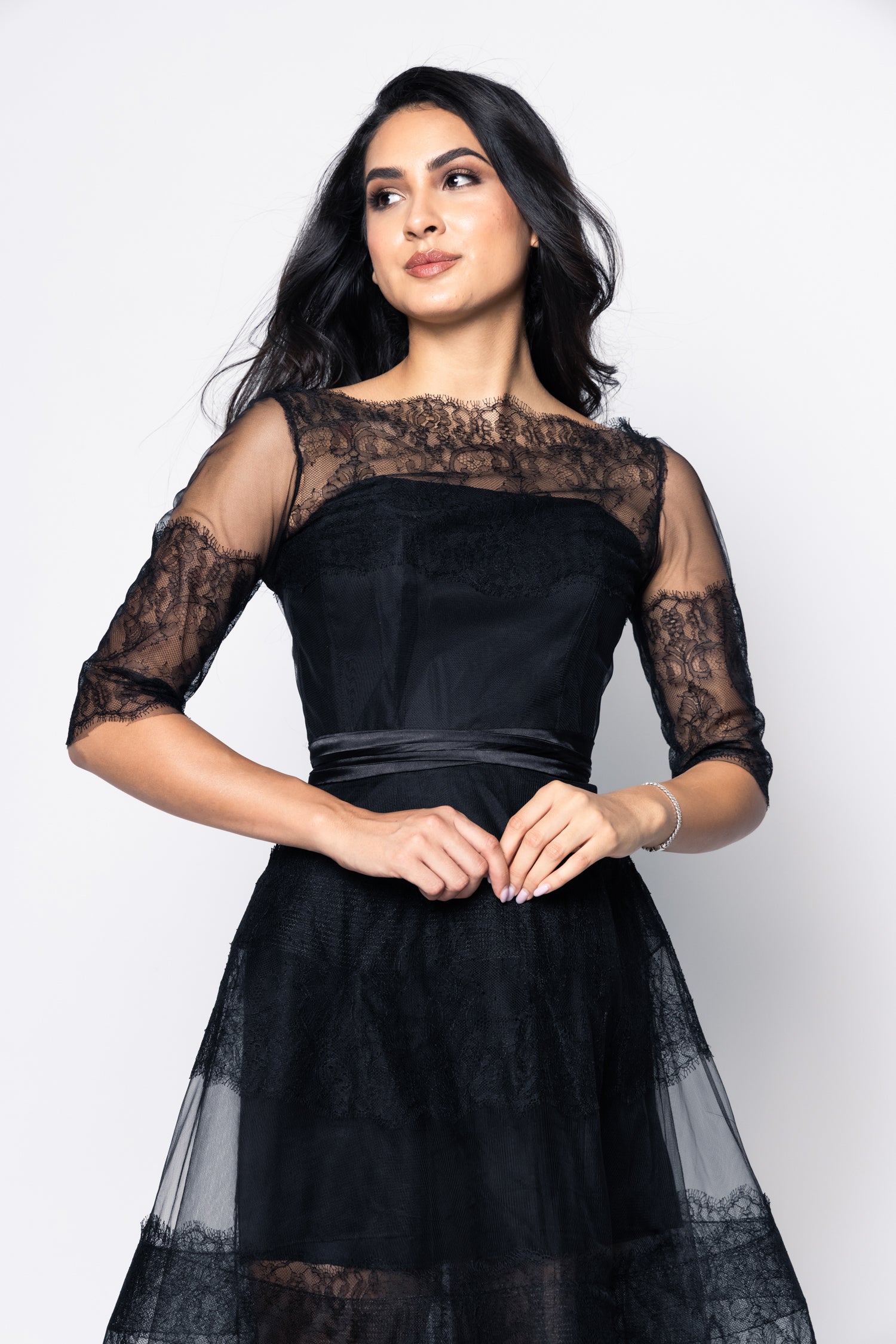 Woman wearing a black lace dress against a white background
