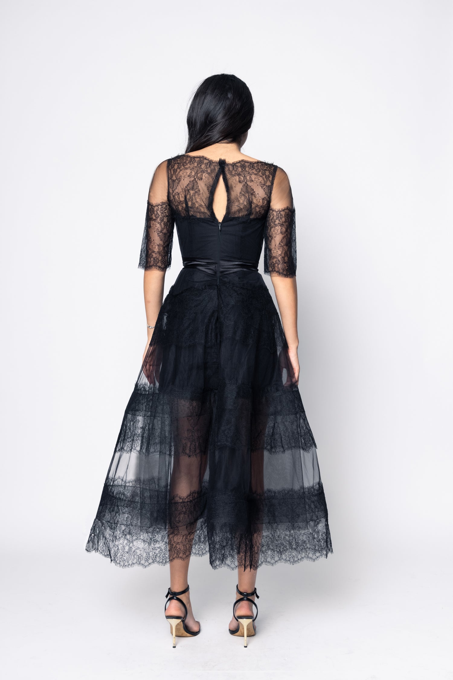 Black lace dress with sheer overlay on a white background