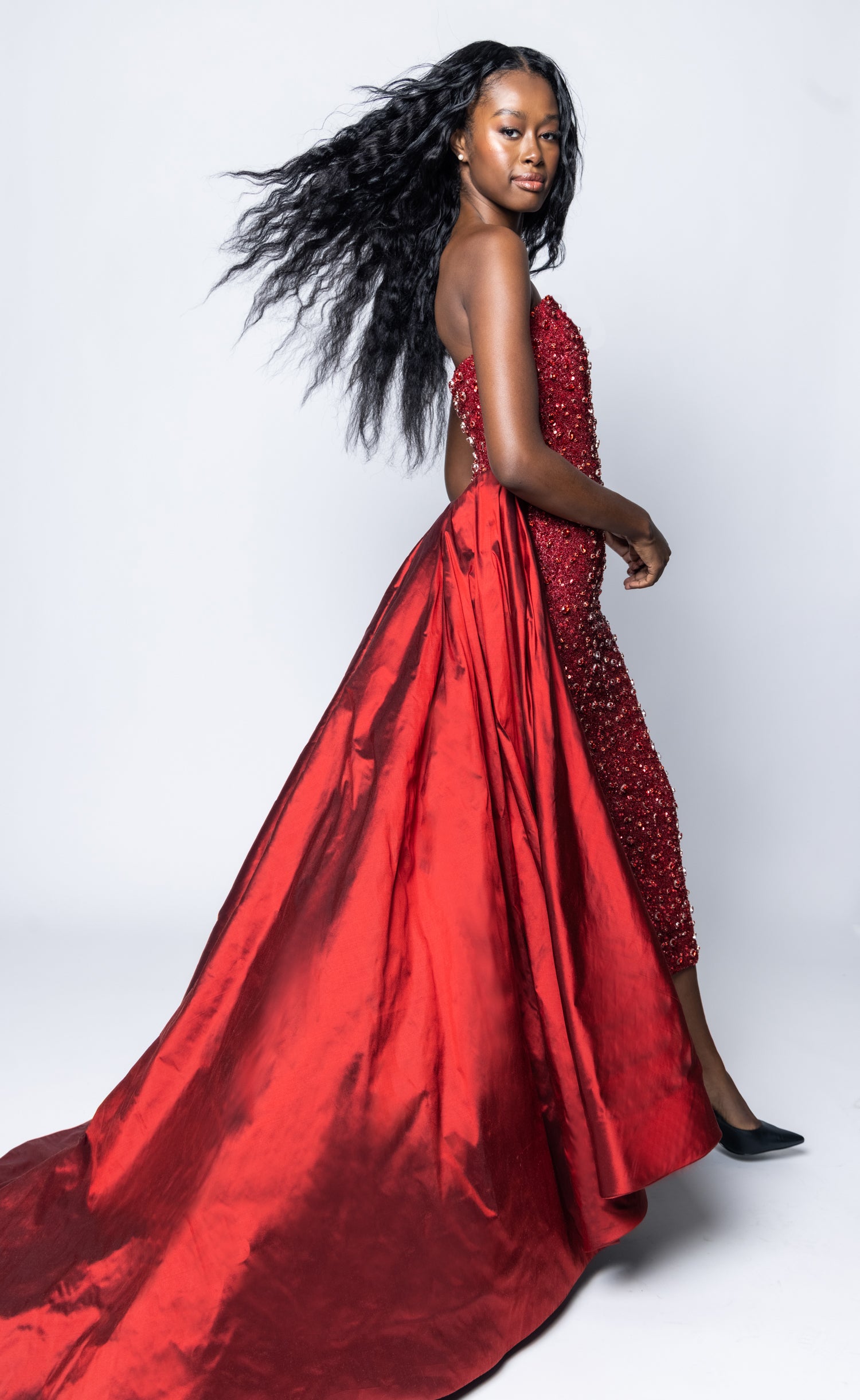 Woman wearing a red evening gown with a white background