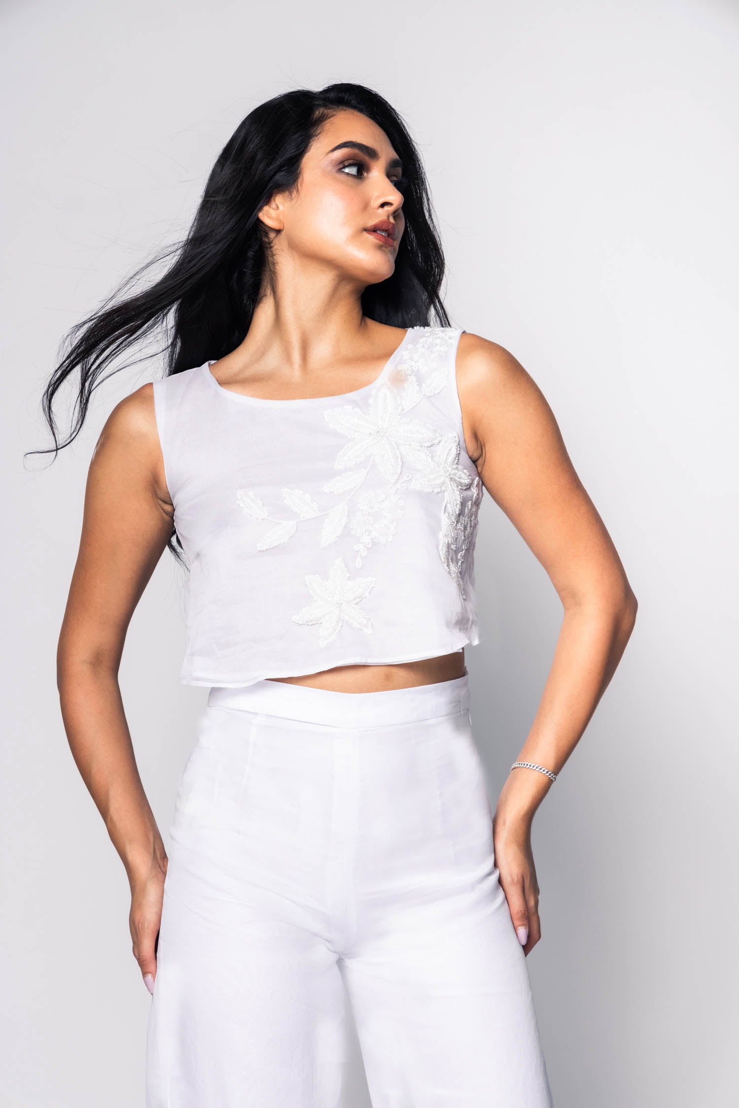Woman wearing a white beaded outfit with a plain background
