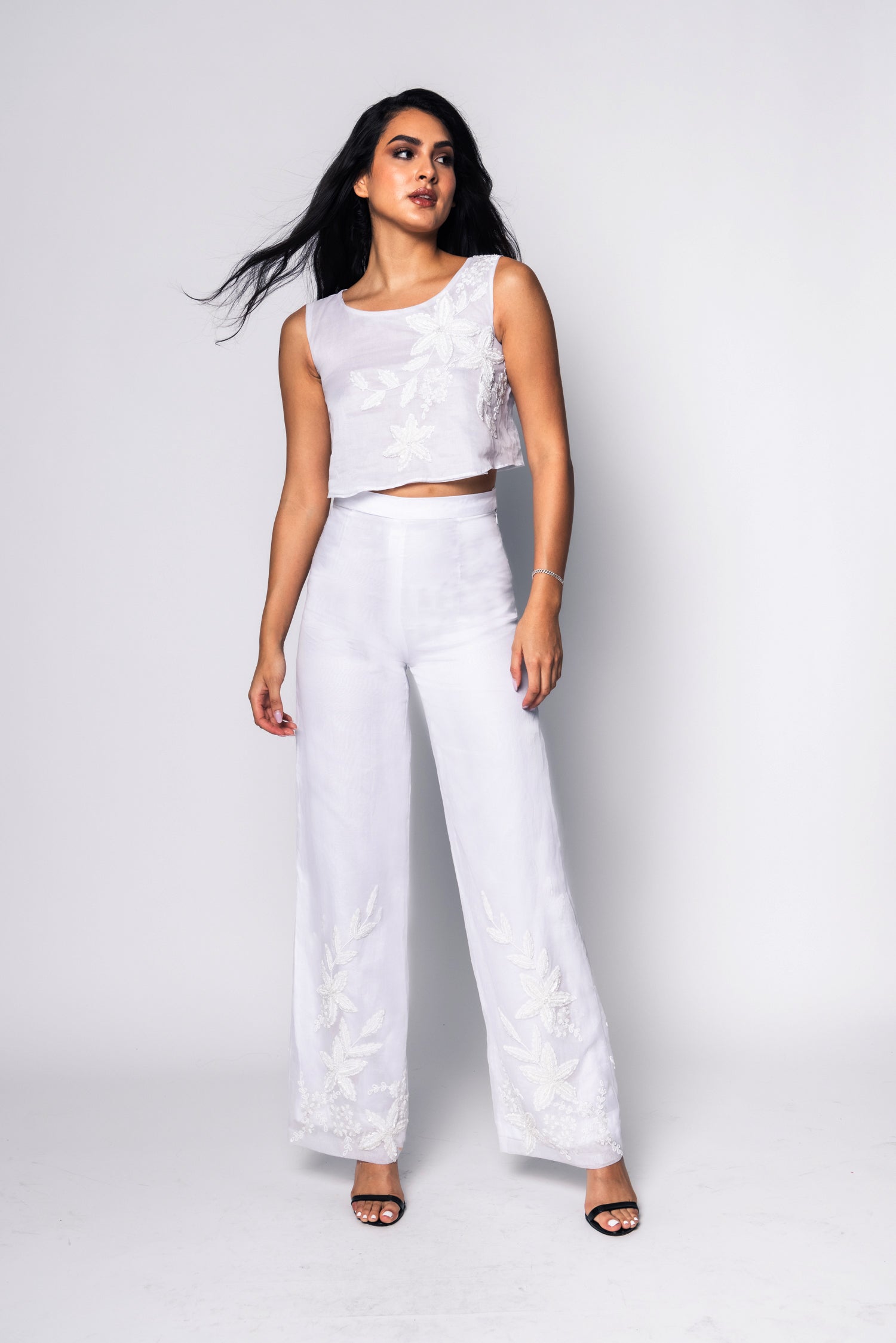 Woman wearing a white beaded outfit with a plain background