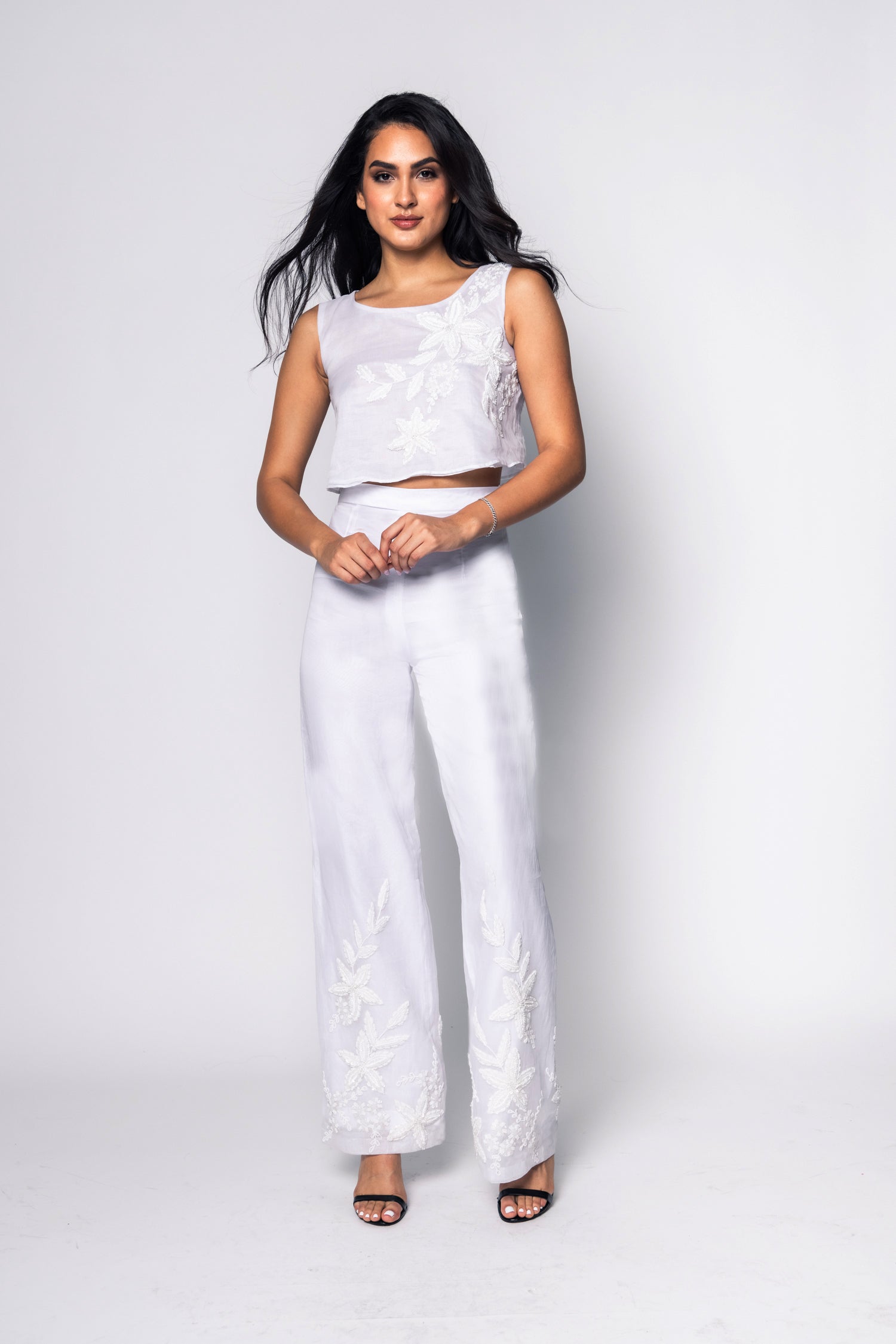 Woman wearing a white outfit with floral patterns on a white background
